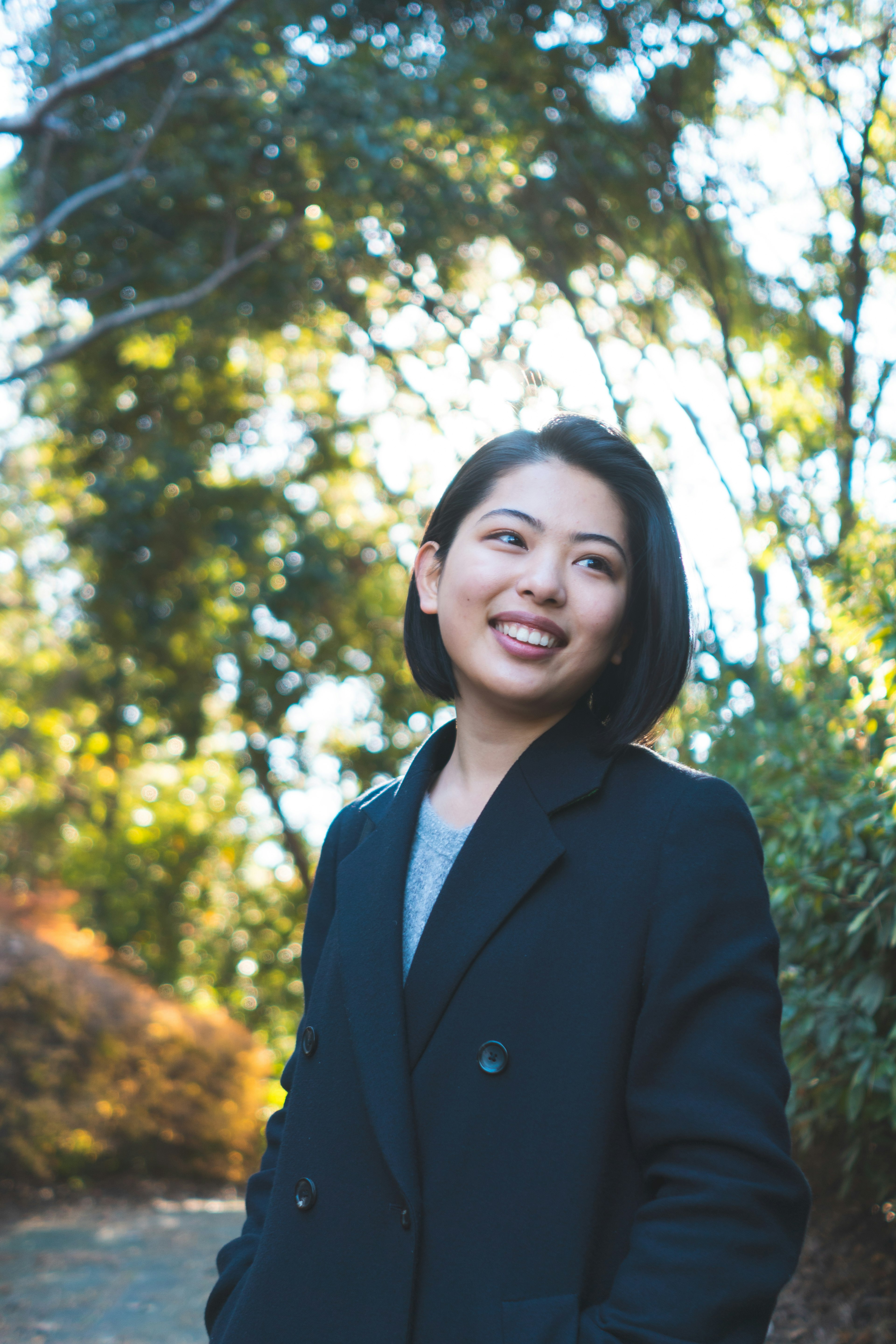 Portrait of a smiling woman in a black coat in a park with a natural background