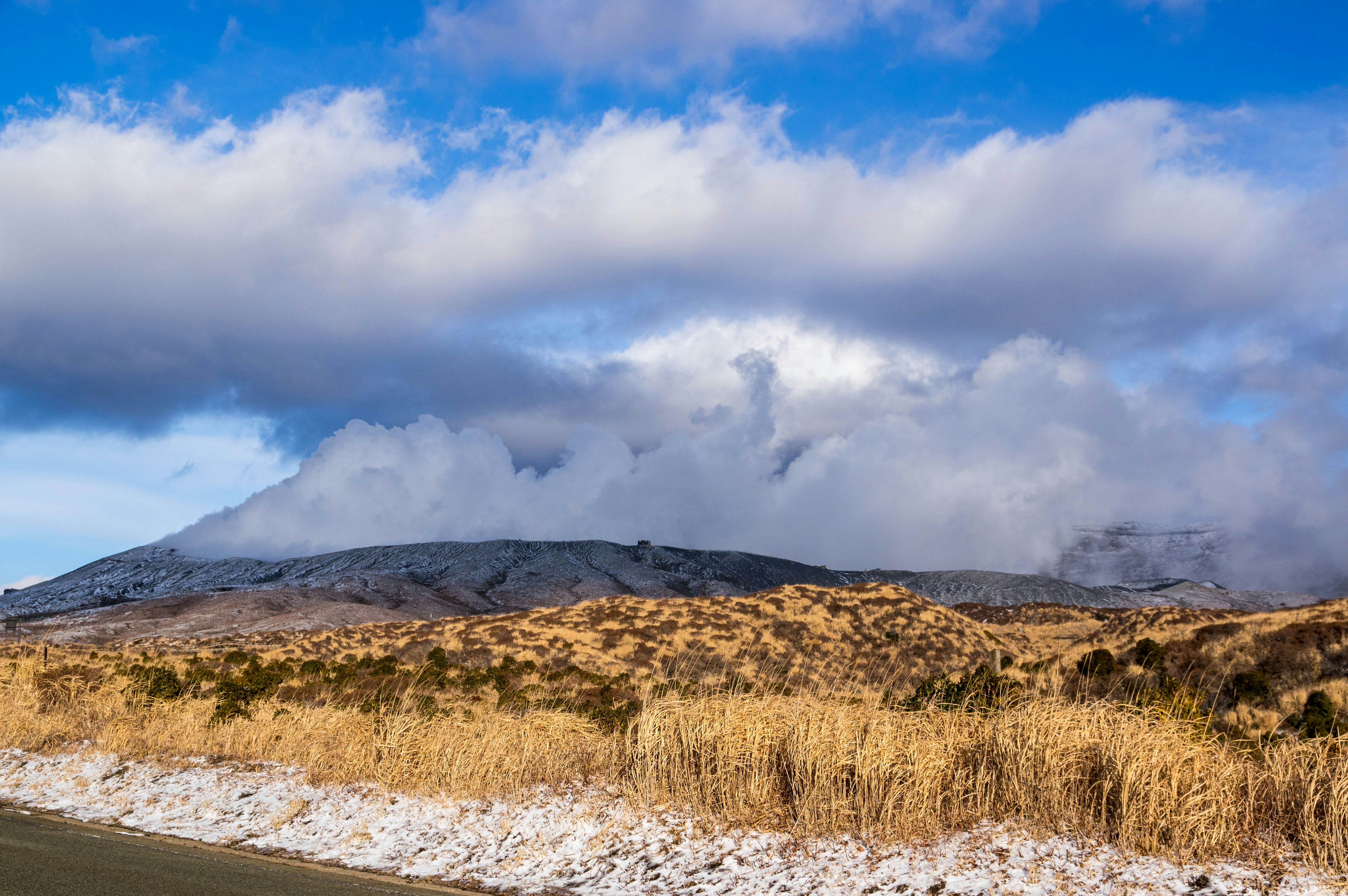 Berglandschaft mit blauem Himmel und weißen Wolken trockene Graslandschaft im Vordergrund