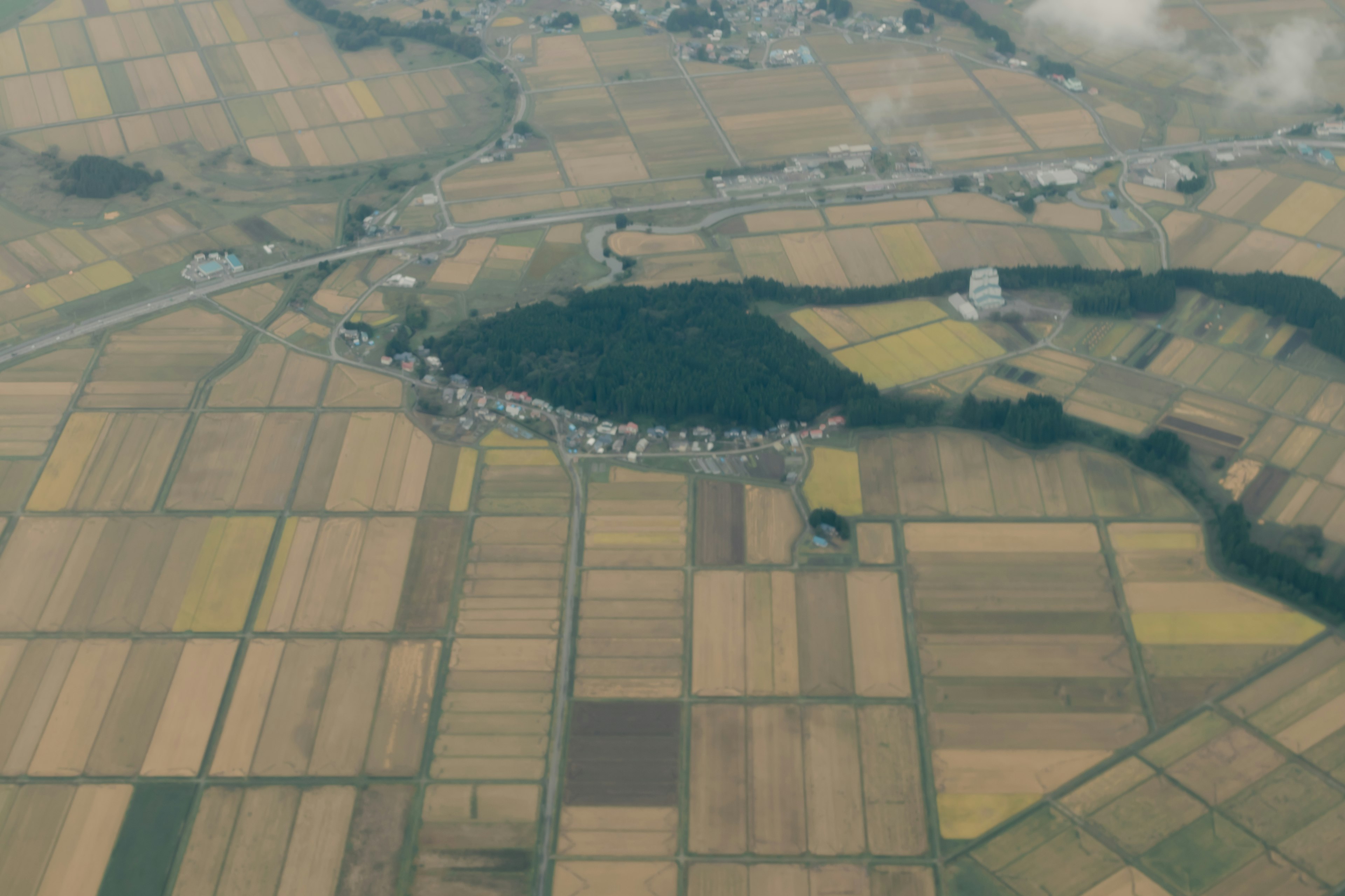 Vista aérea de un paisaje agrícola con campos coloridos y un pequeño pueblo