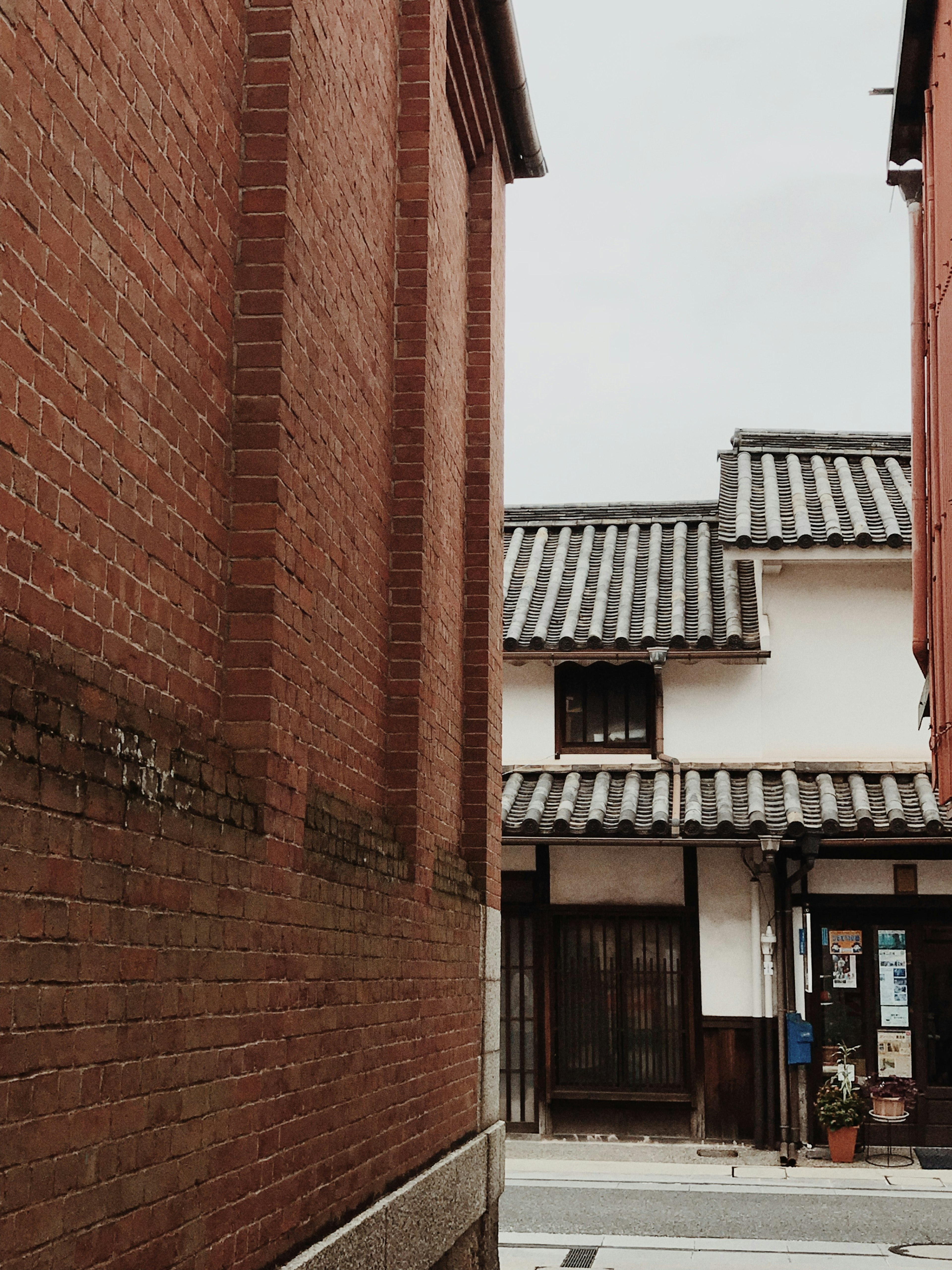 Lorong sempit dengan dinding bata dan rumah atap tradisional