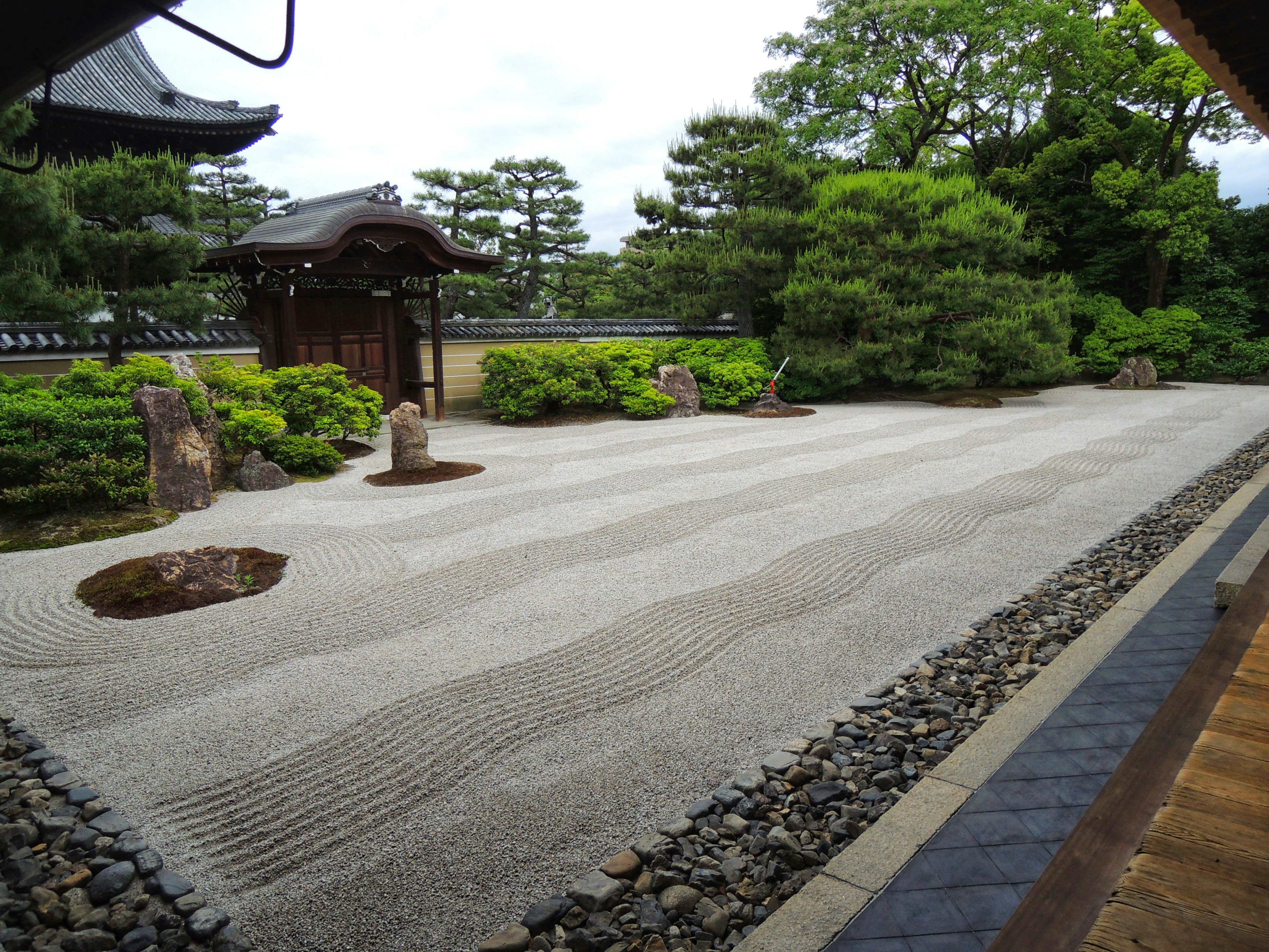 Vue sereine d'un jardin japonais avec des chemins en gravier et une végétation luxuriante