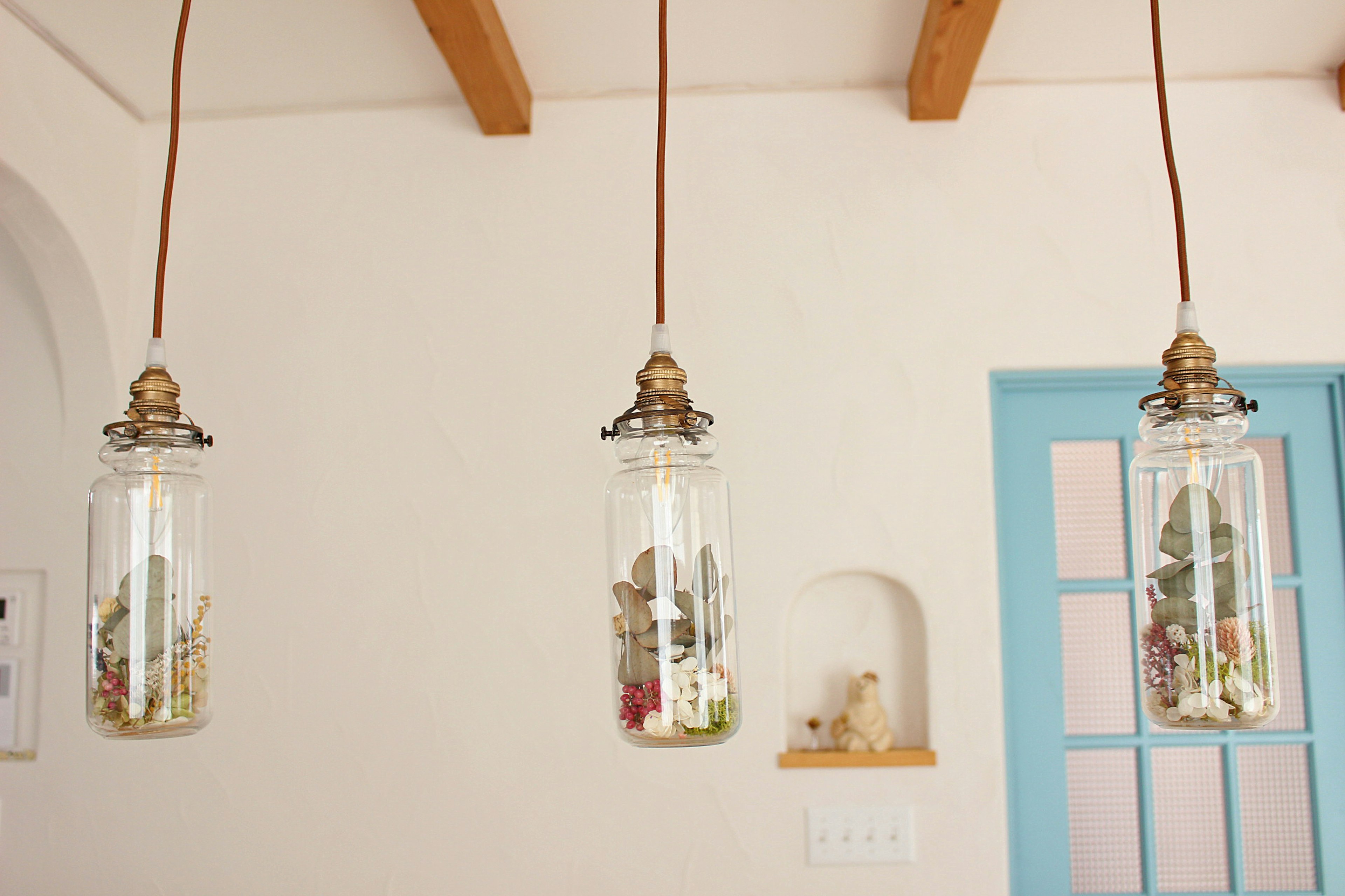 Lampes en verre suspendues avec des arrangements floraux et des plantes dans un intérieur lumineux