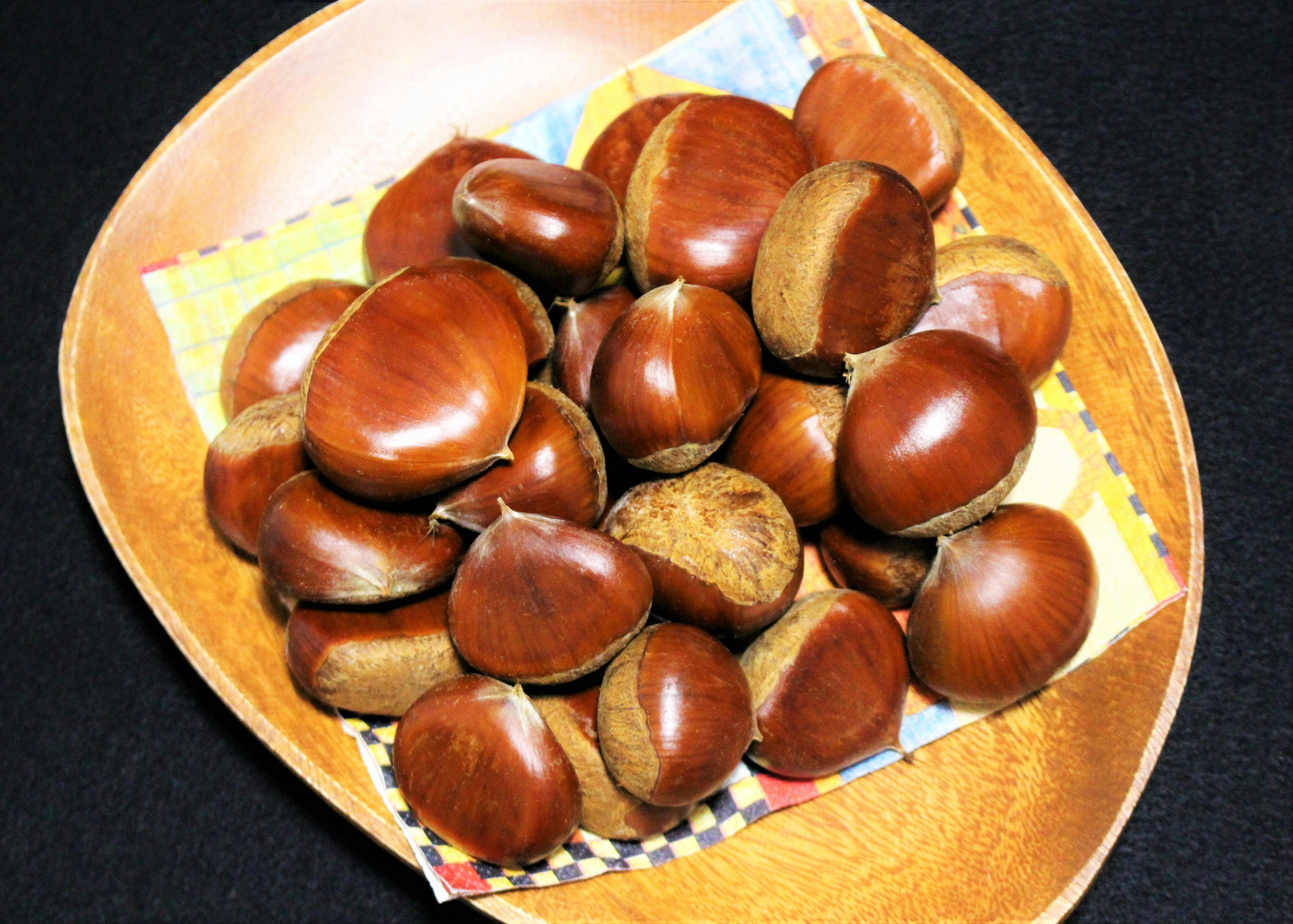 A collection of chestnuts in a wooden bowl