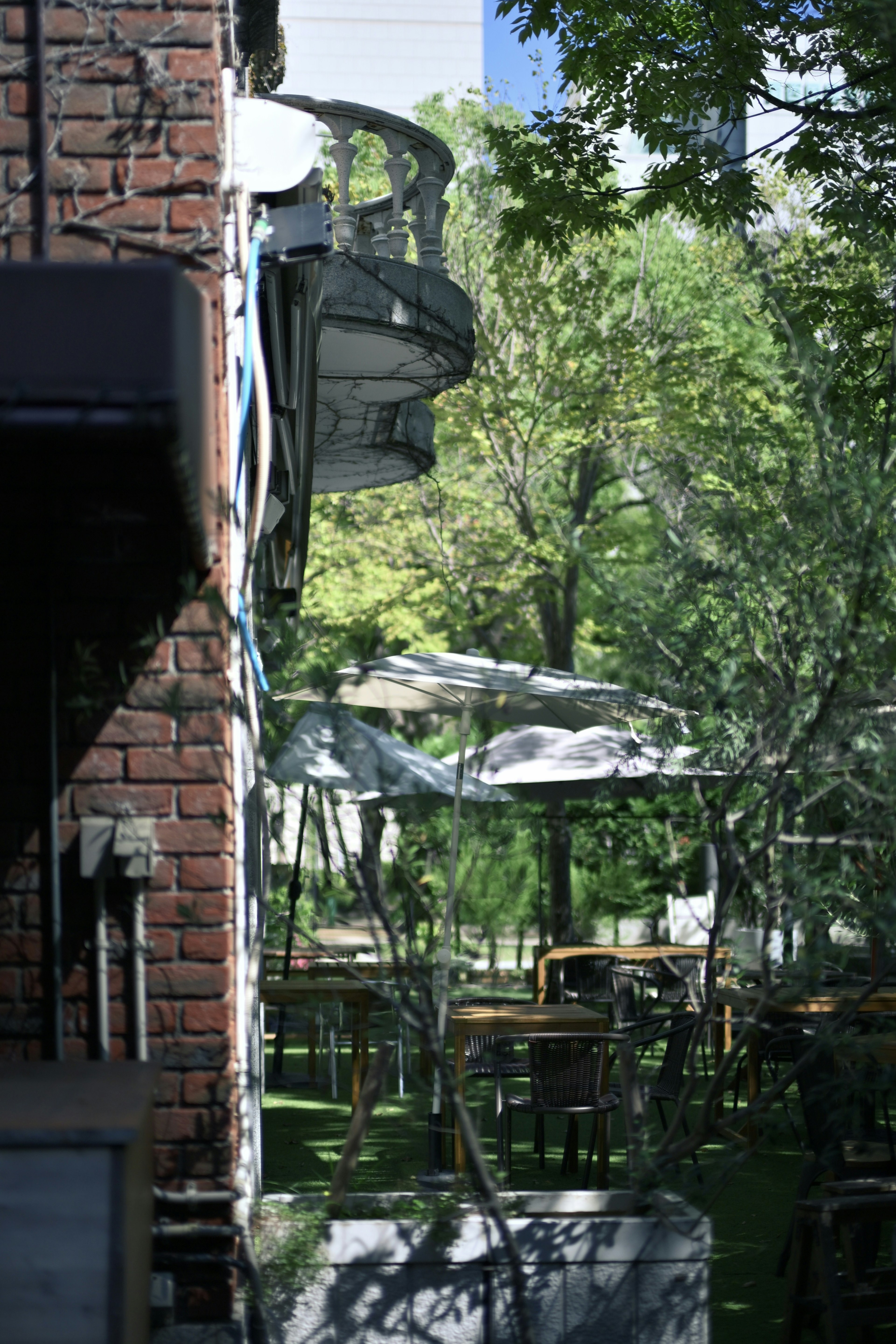 Café-Terrasse umgeben von Grün mit einer Ziegelmauer