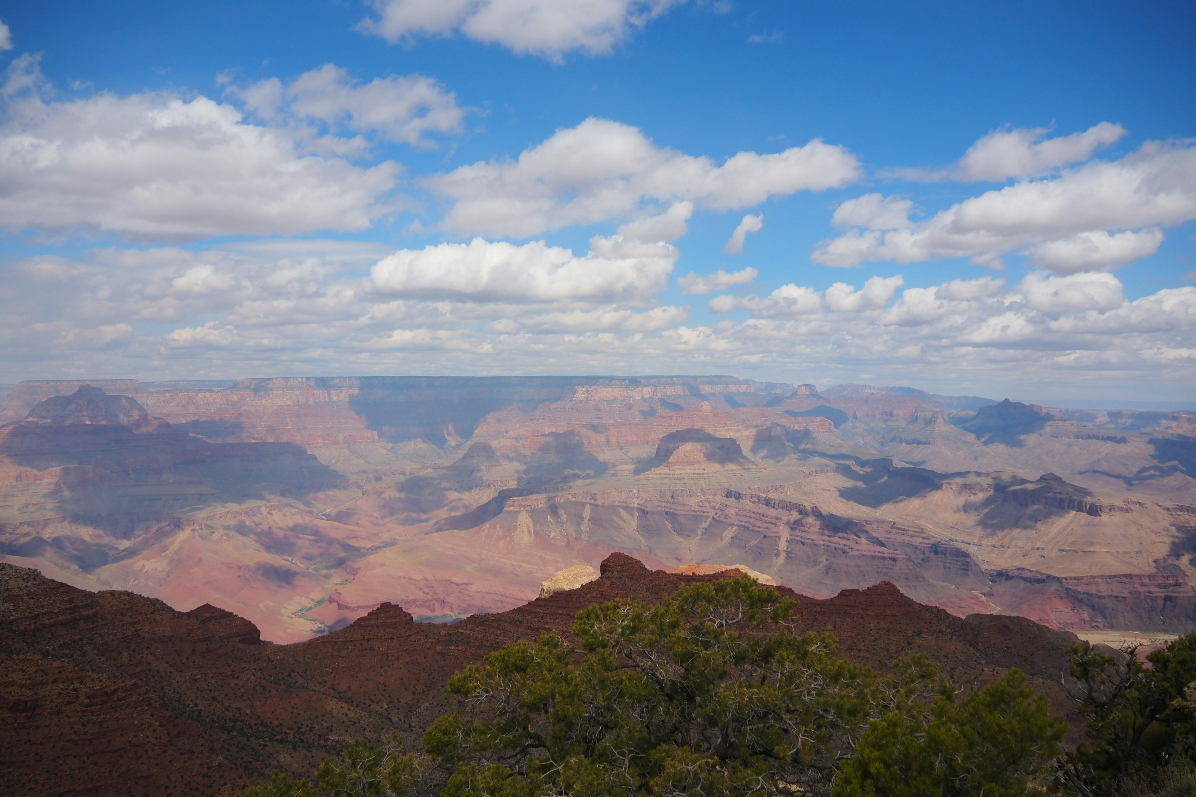 Vista expansiva del Gran Cañón con cielo azul y nubes blancas