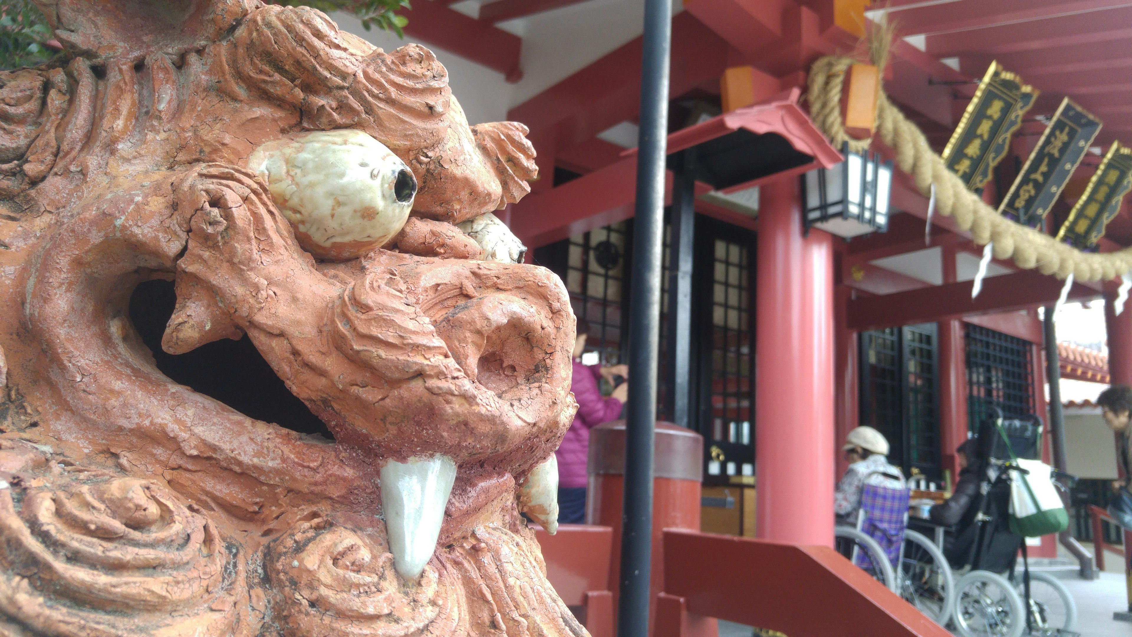 Lion sculpture with large eyes and fangs in front of a red building