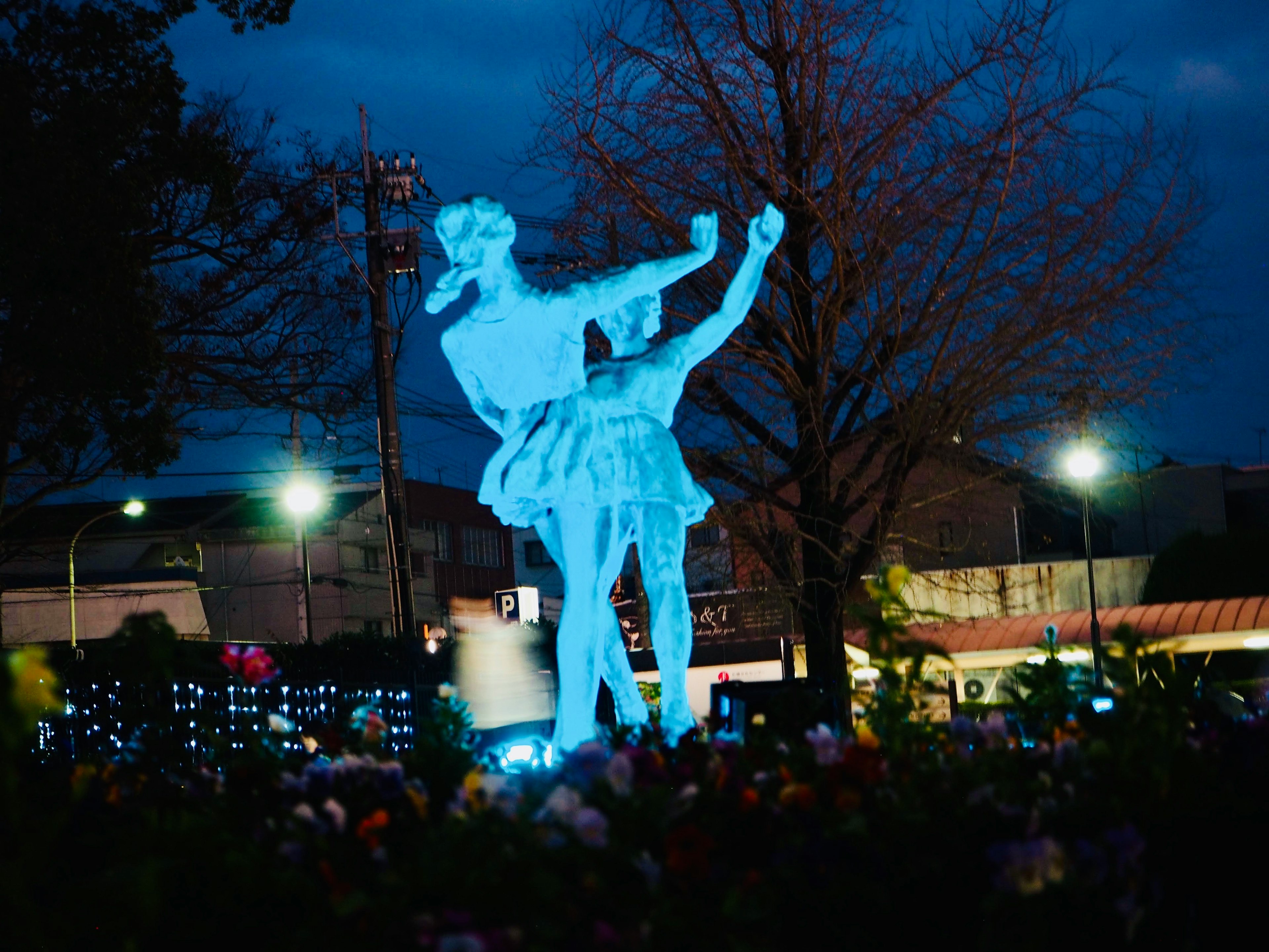 Una statua di danza illuminata di blu contro un cielo notturno