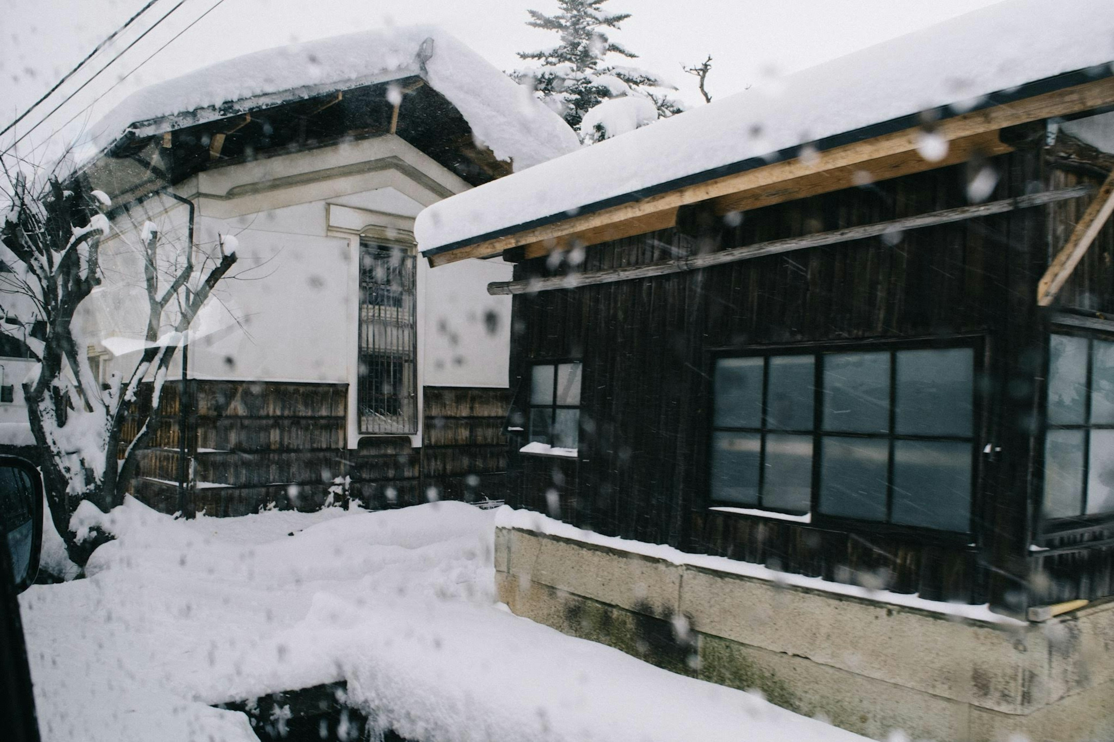 Traditionelle japanische Häuser, die mit Schnee bedeckt sind, mit einem modernen Gebäude