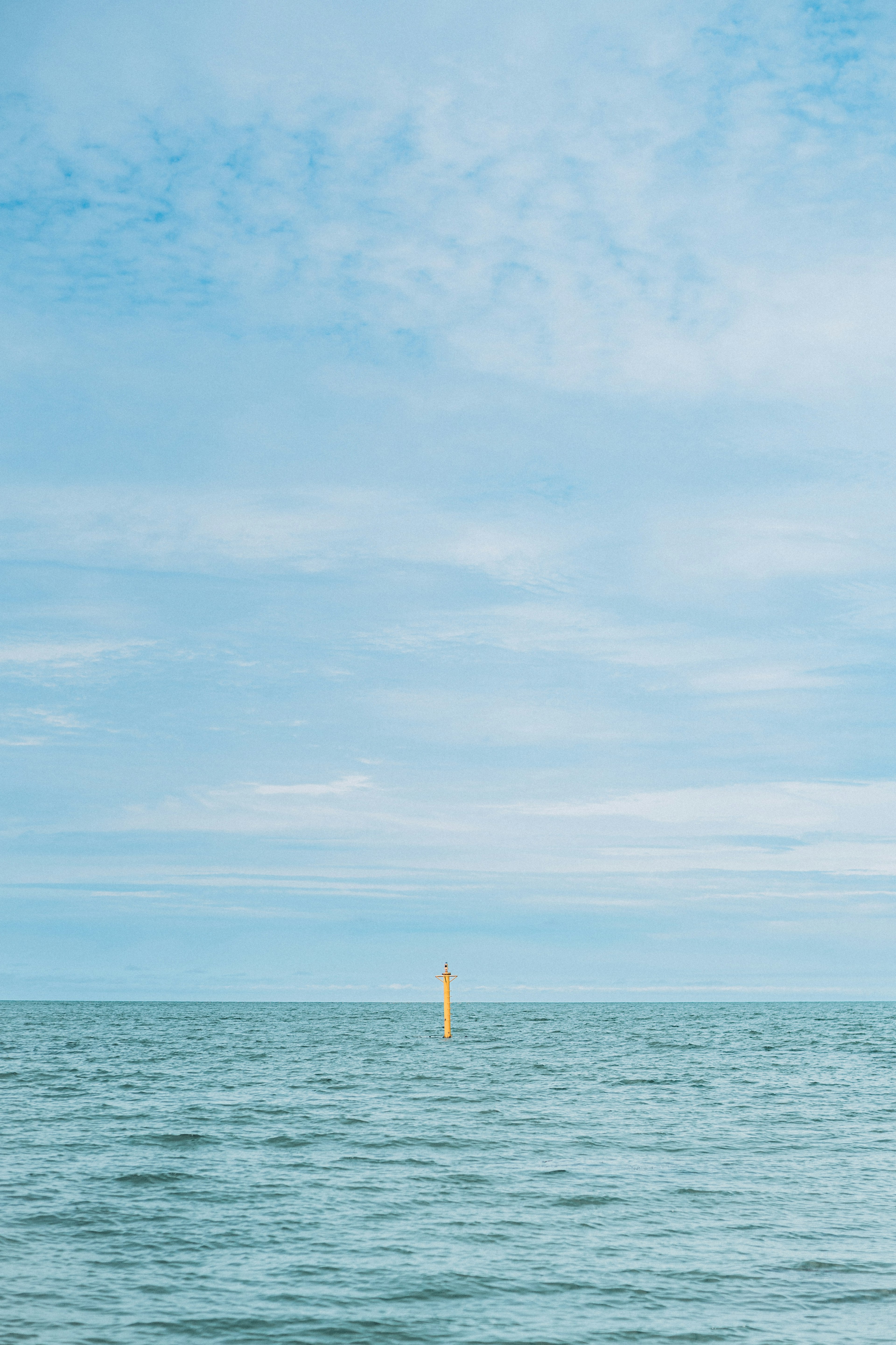 Mer calme avec ciel dégagé bouée jaune flottant sur l'eau