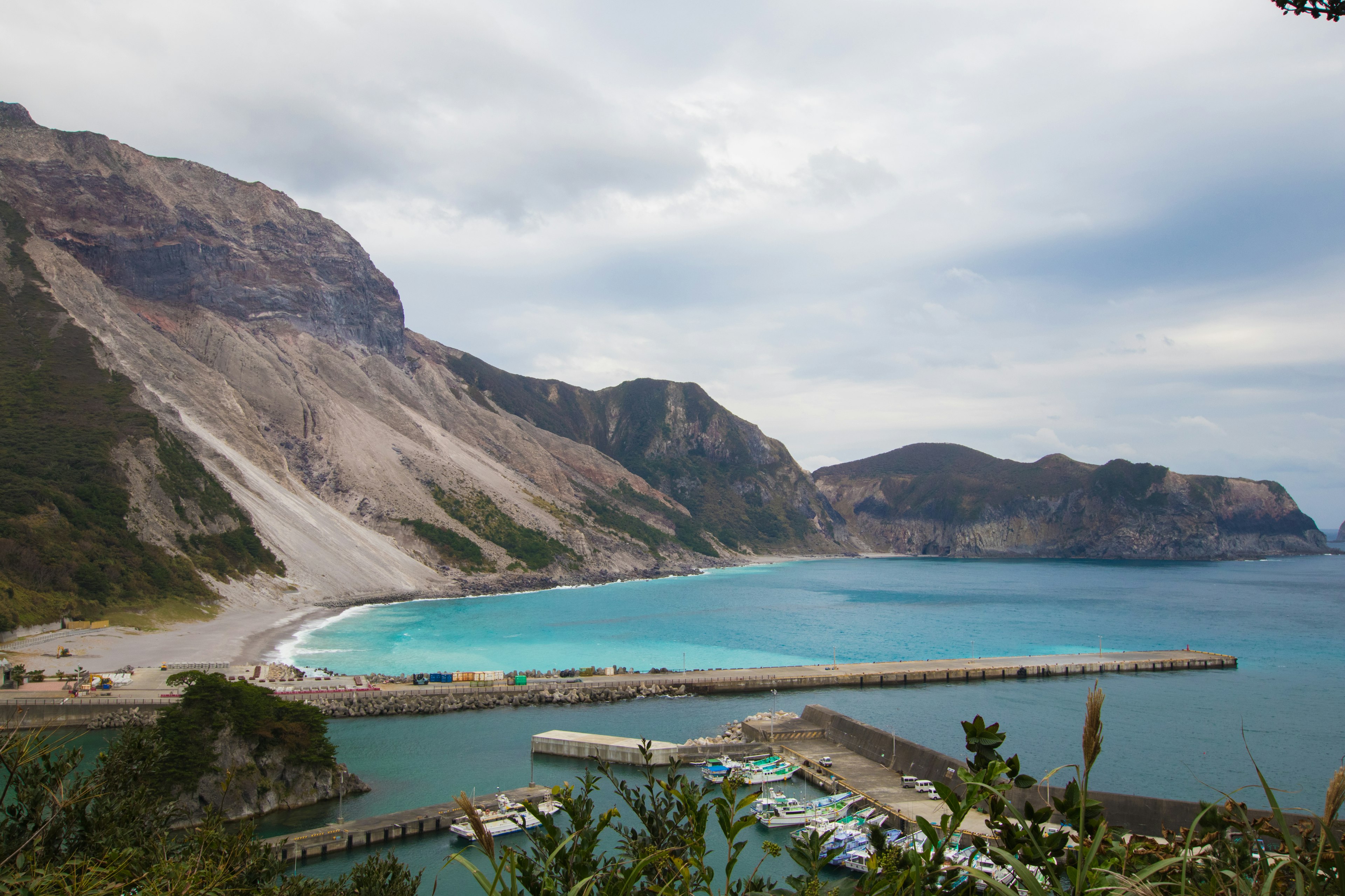 Vista panorámica de un océano azul y montañas con un puerto y una playa de arena