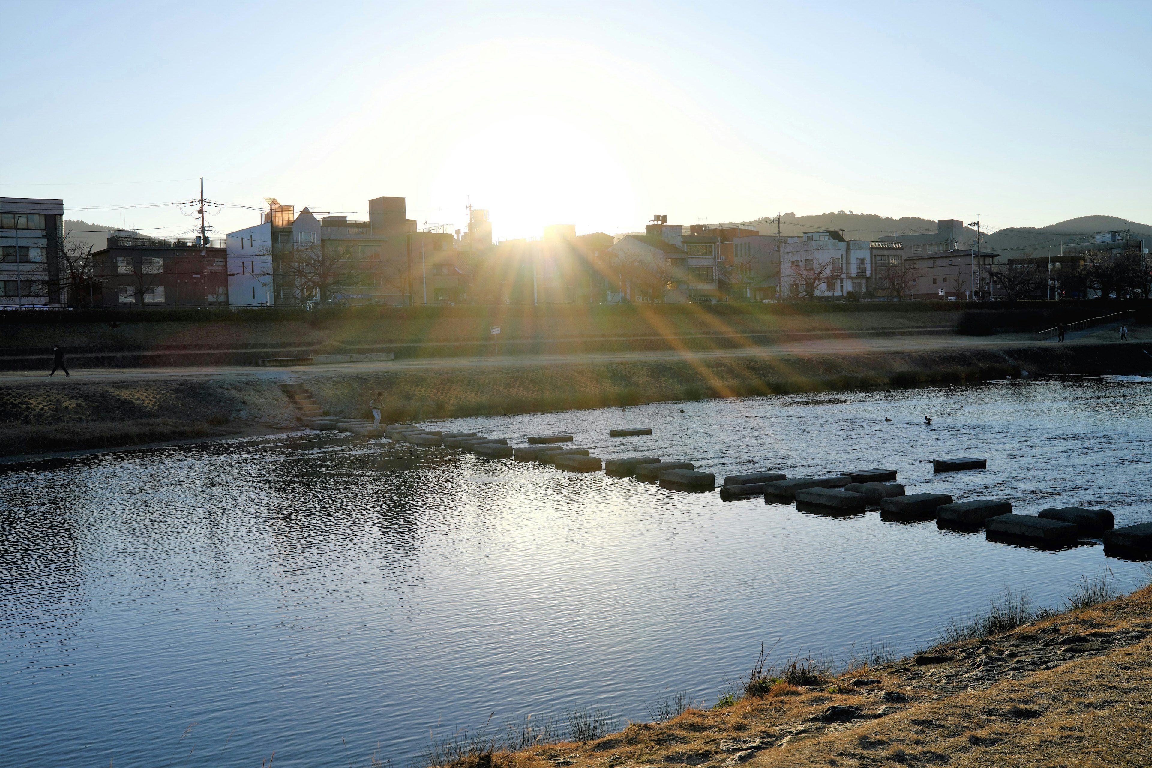 Una escena serena de un río con piedras y un brillante atardecer