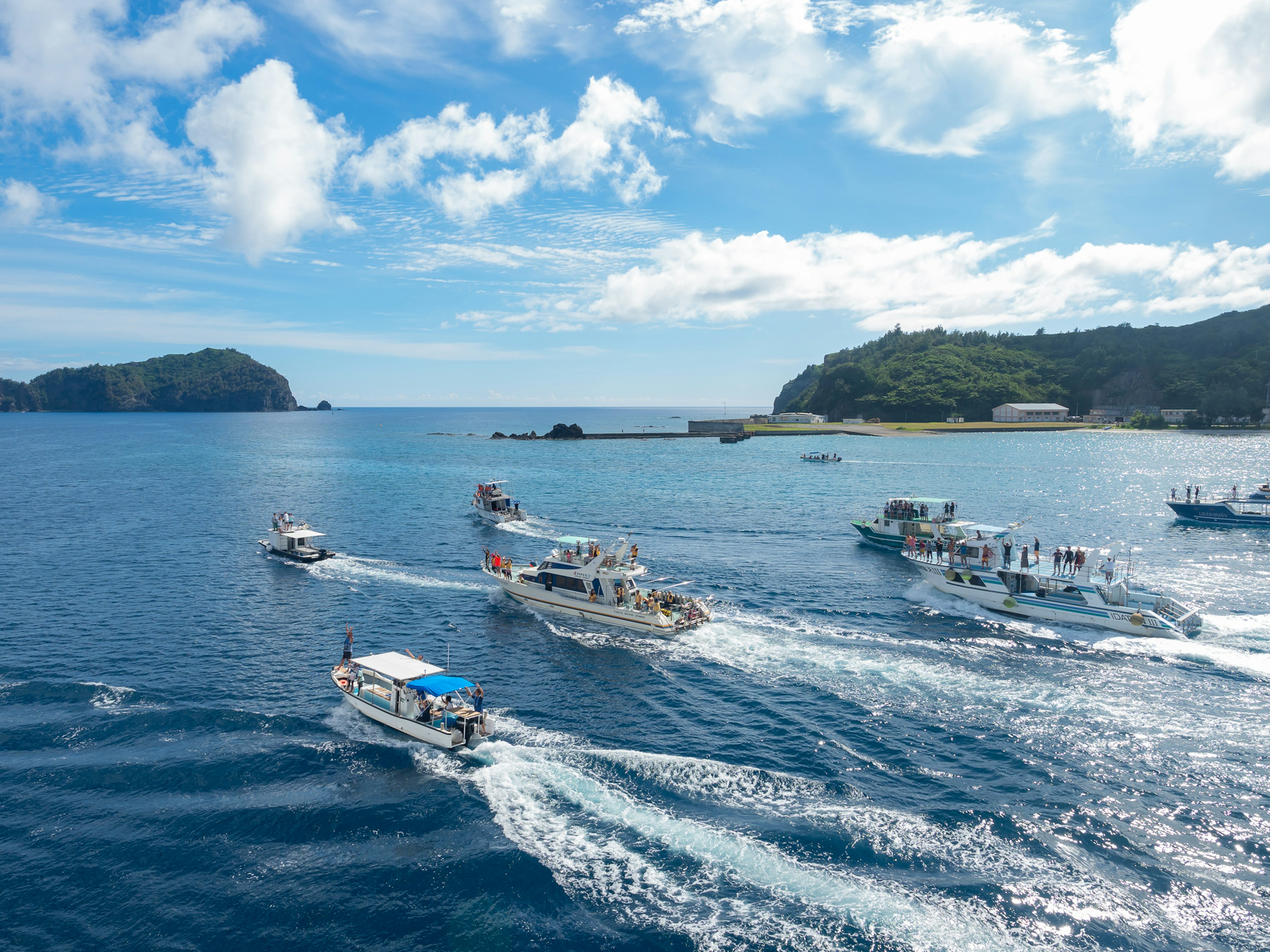 Aerial view of multiple boats navigating in blue waters under a clear sky