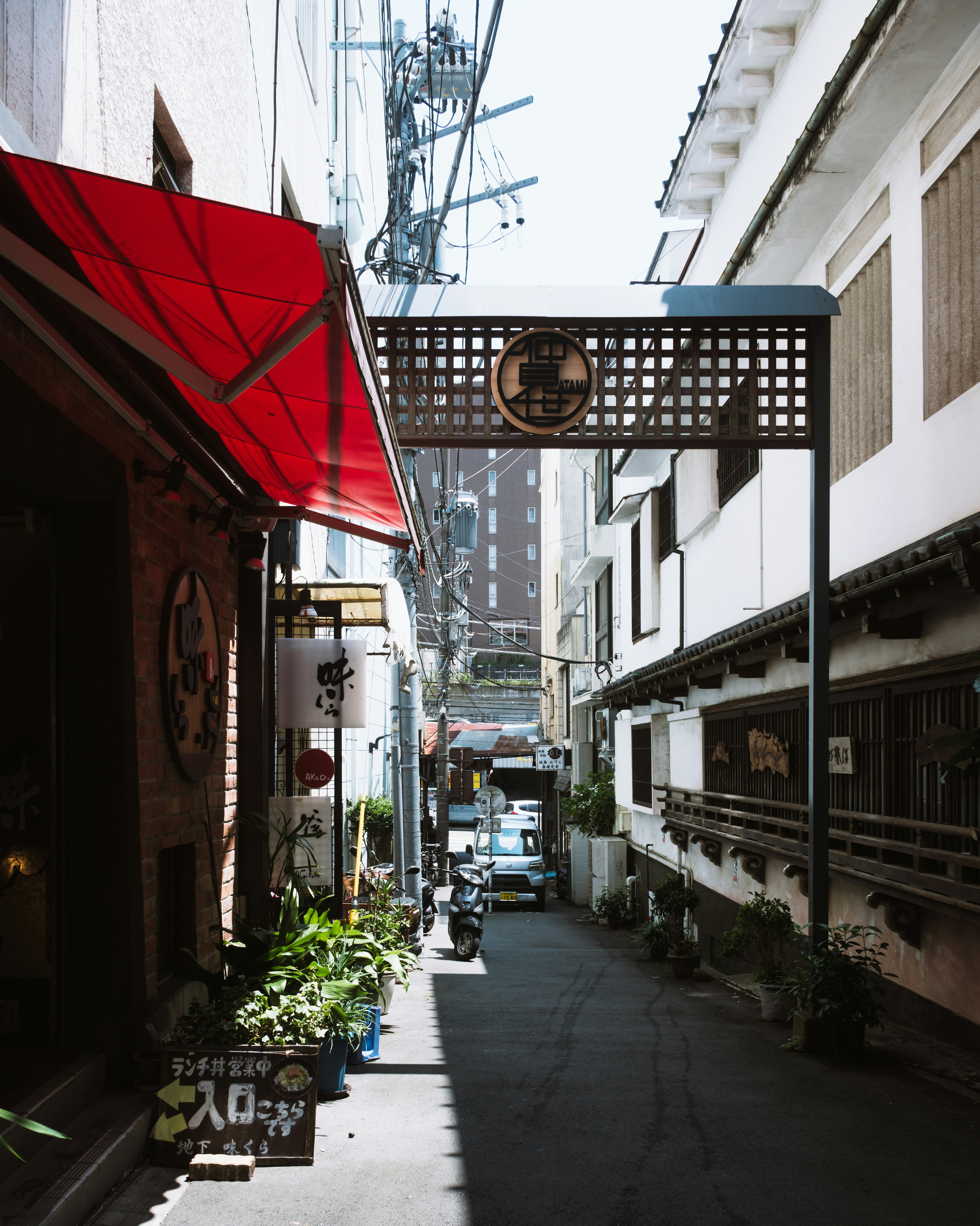 Narrow alley with a red awning and an archway sign between tall buildings