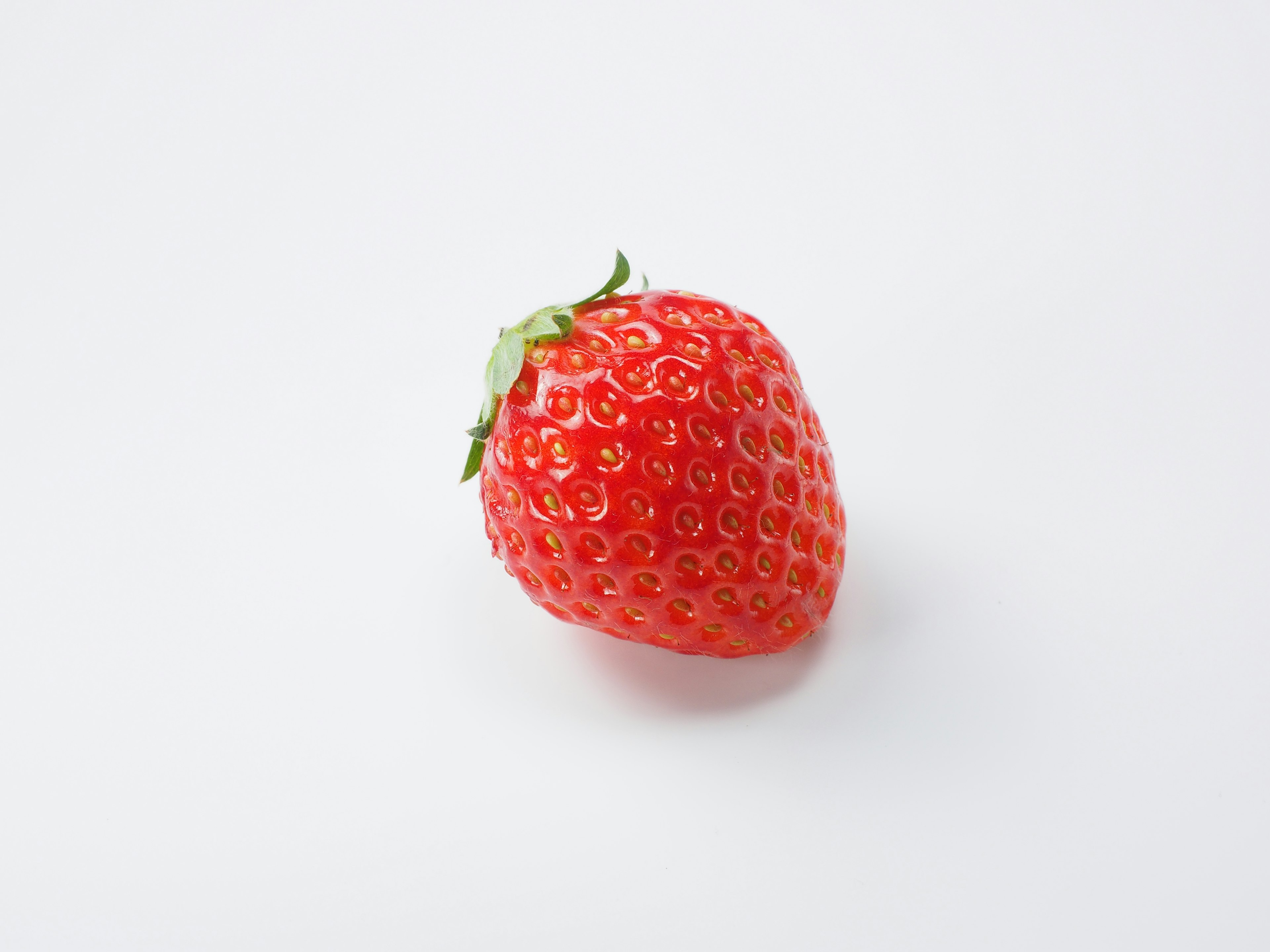 A single vibrant red strawberry on a white background