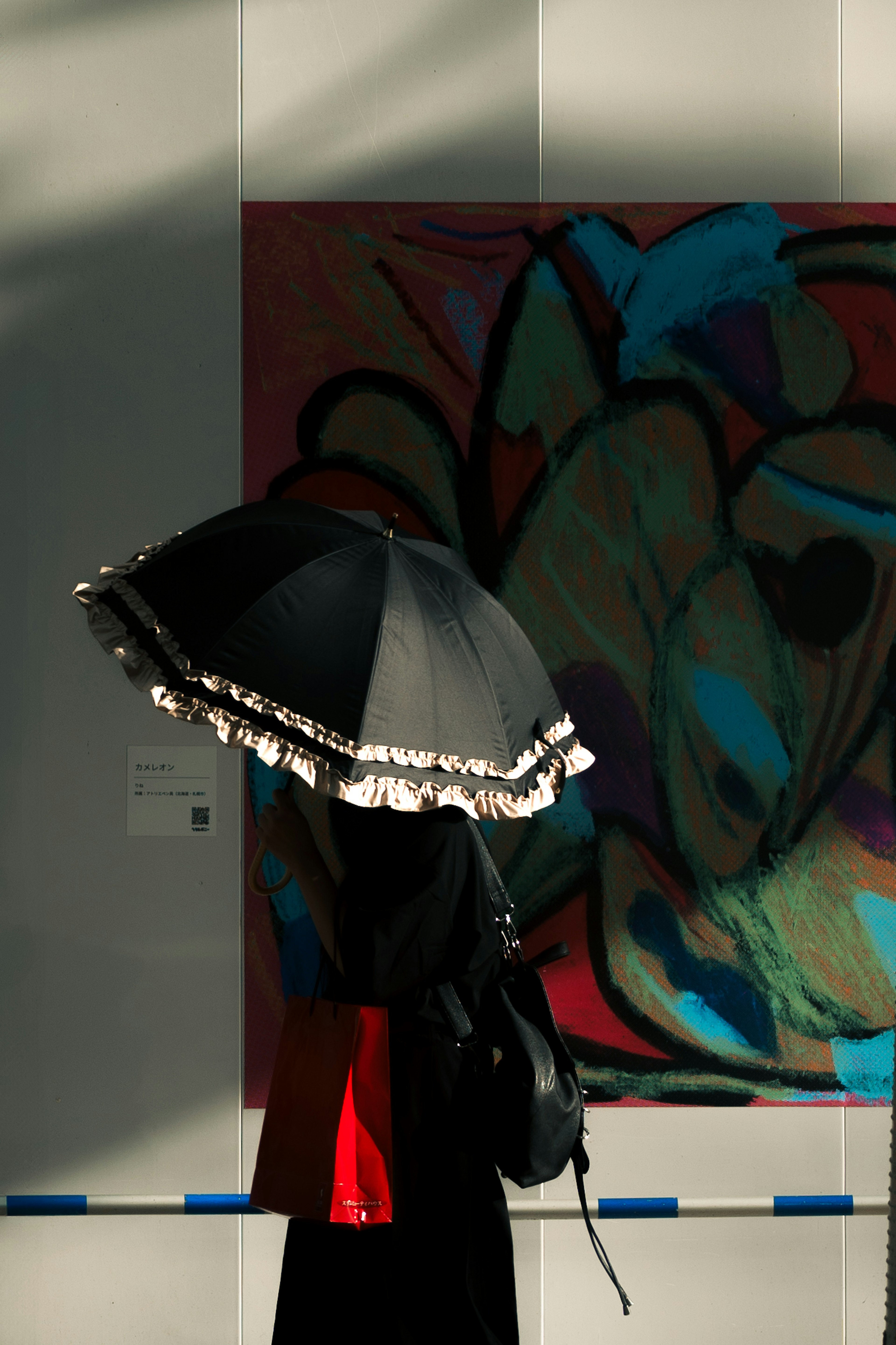 Person holding a black parasol with colorful art background