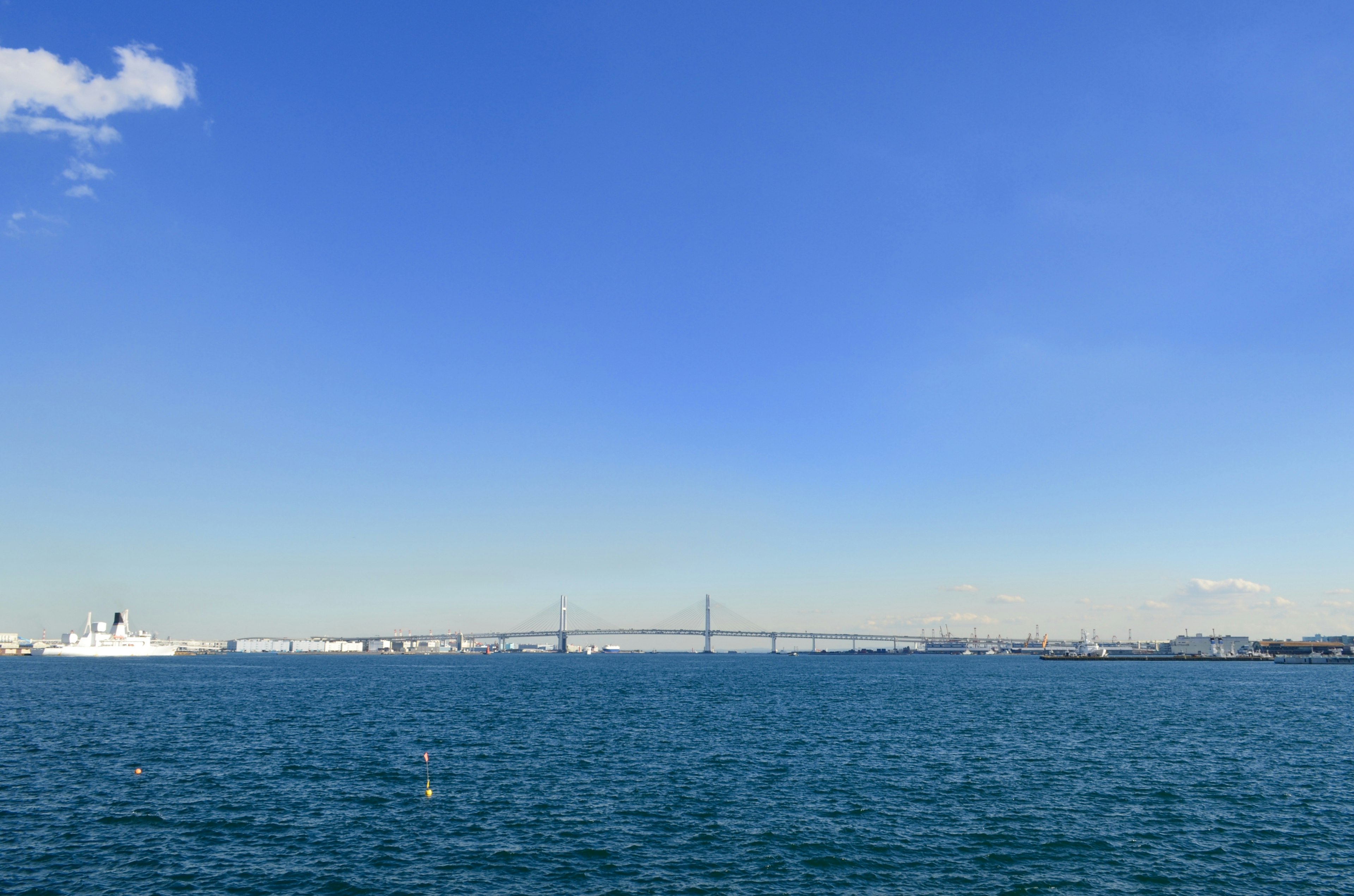 在晴朗的藍天下和寧靜的海面上，有一座橋和船隻的風景