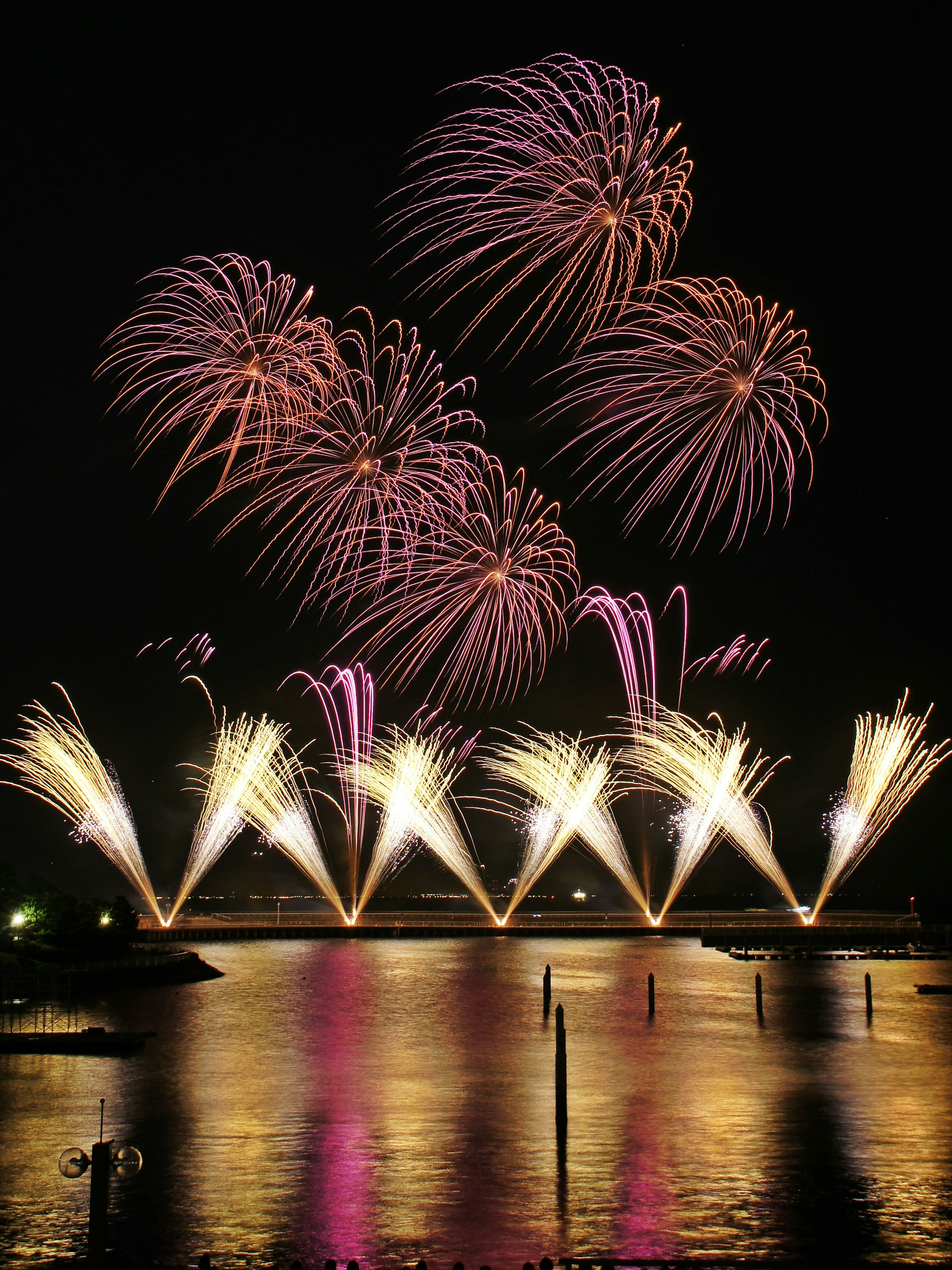 Fuochi d'artificio colorati che esplodono nel cielo notturno riflettendosi sull'acqua