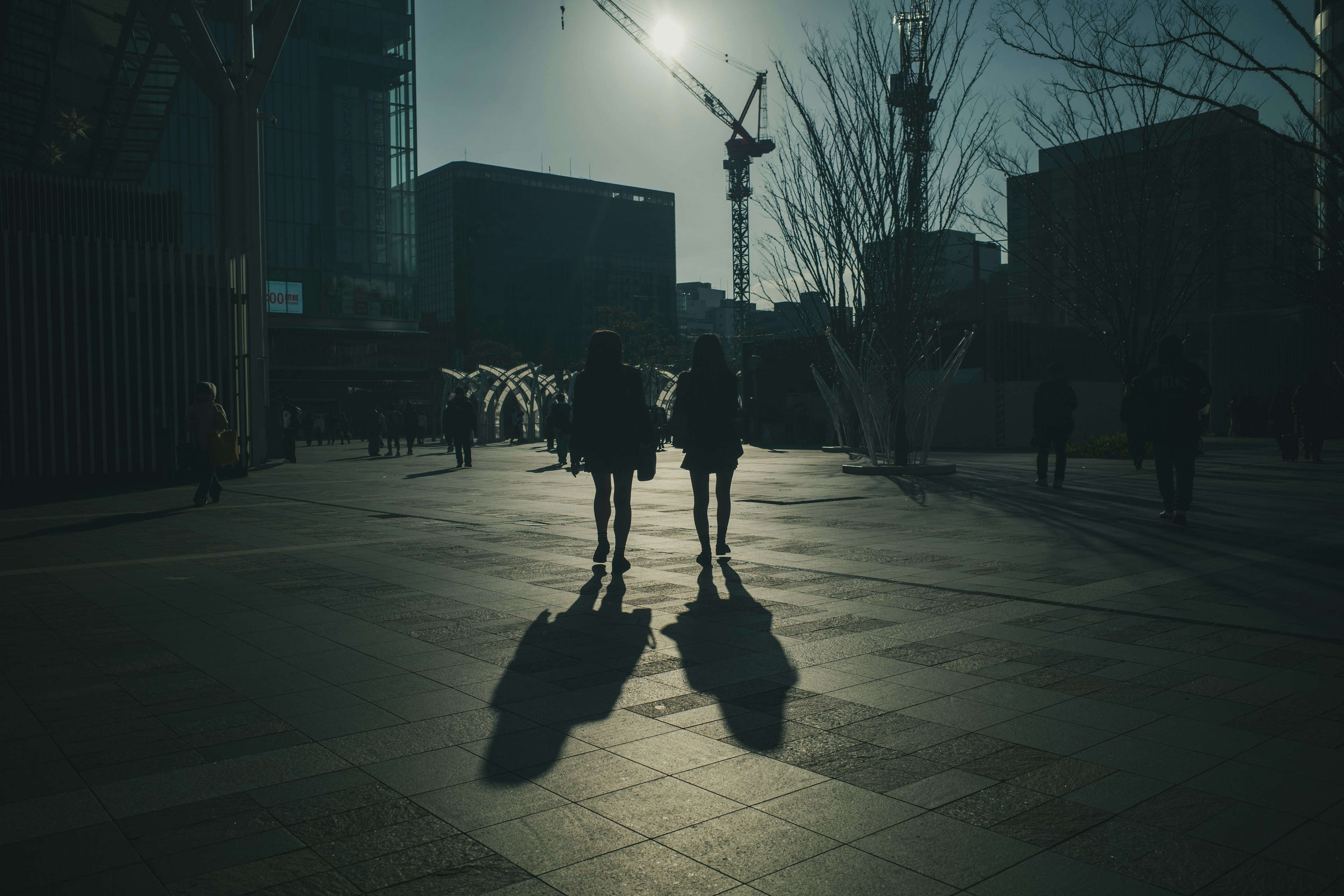 影の中を歩く二人の人影と背景の建物