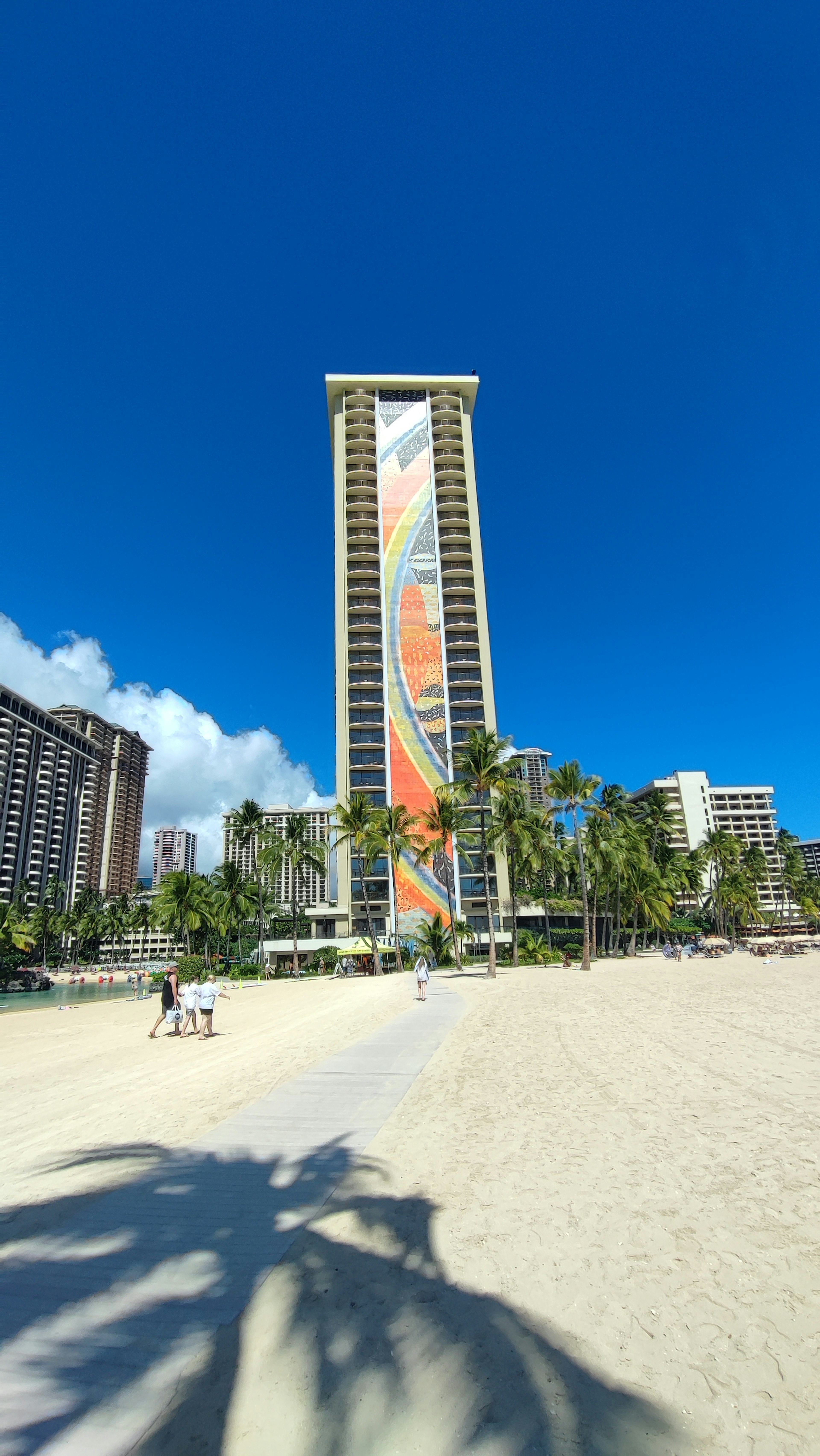 Tall building with colorful banner in front of a beach under a clear blue sky