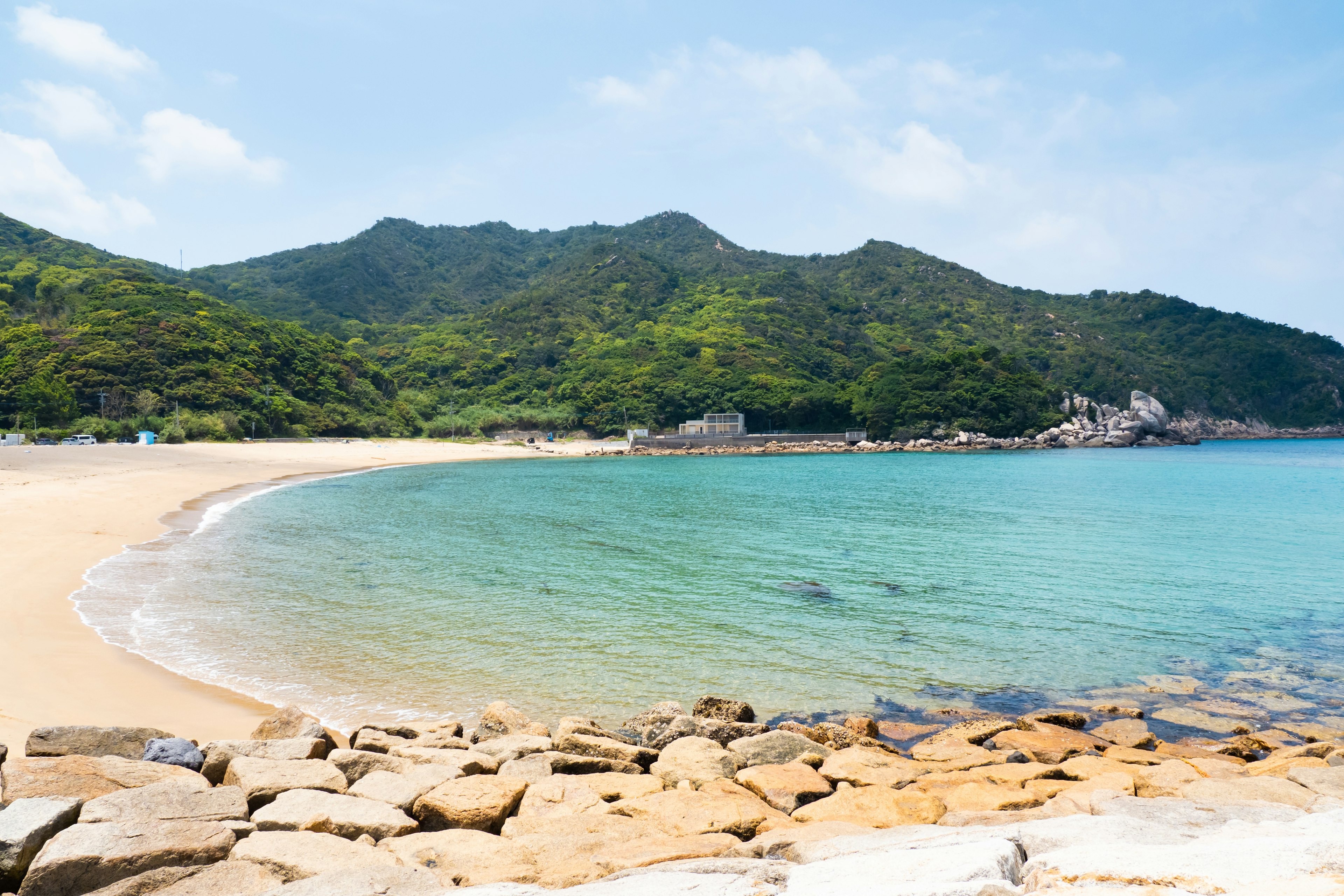 Scenic beach view with blue water and green mountains in the background