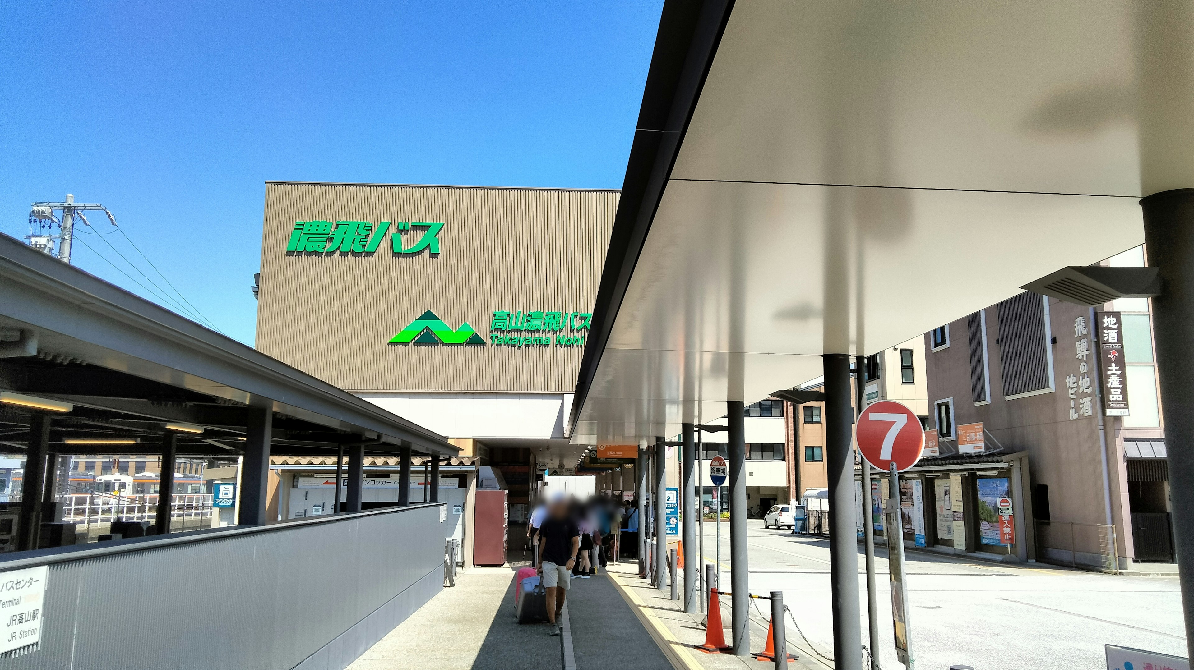 Photo of a bus stop and surrounding buildings under a blue sky