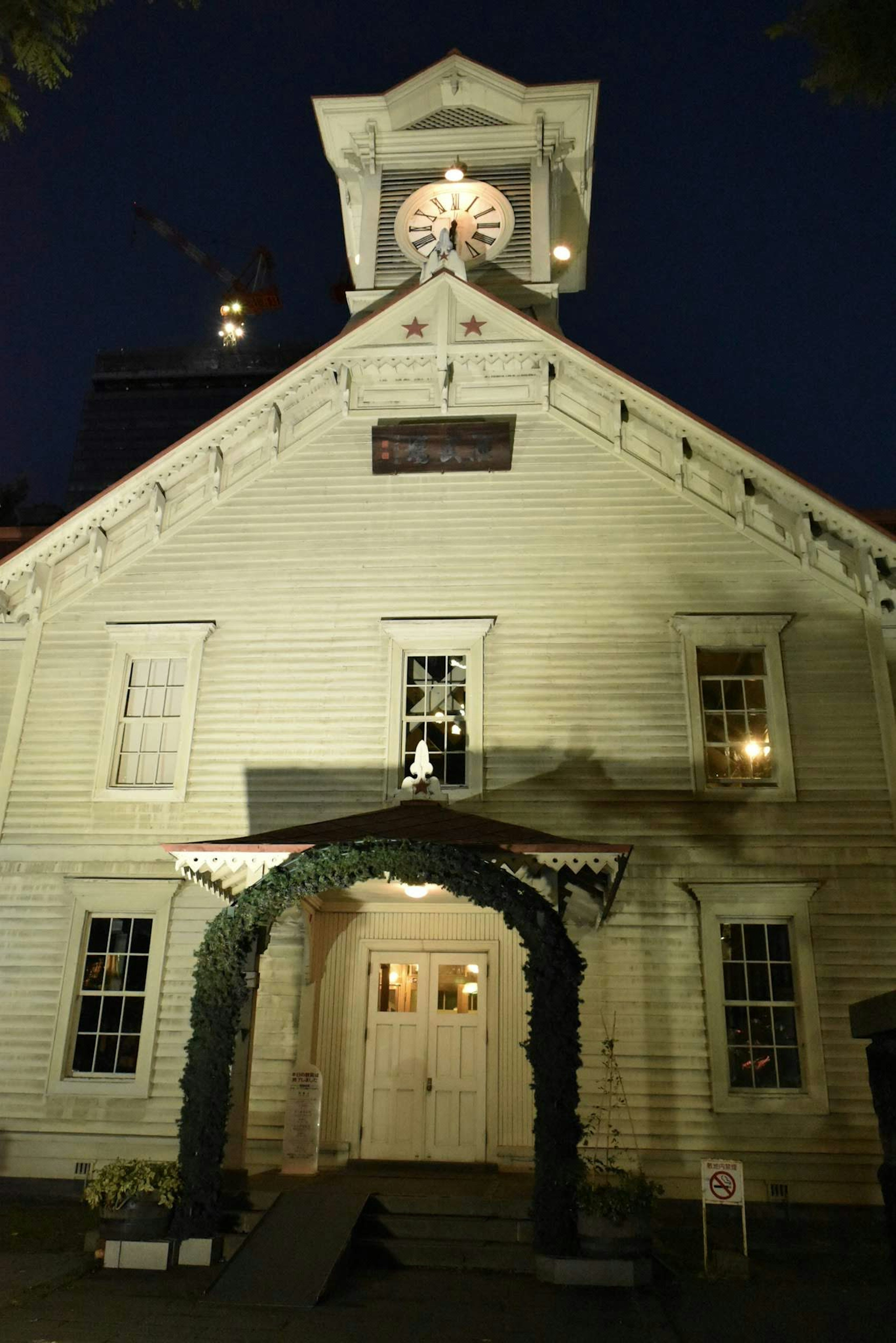 White wooden building illuminated at night featuring a prominent clock tower