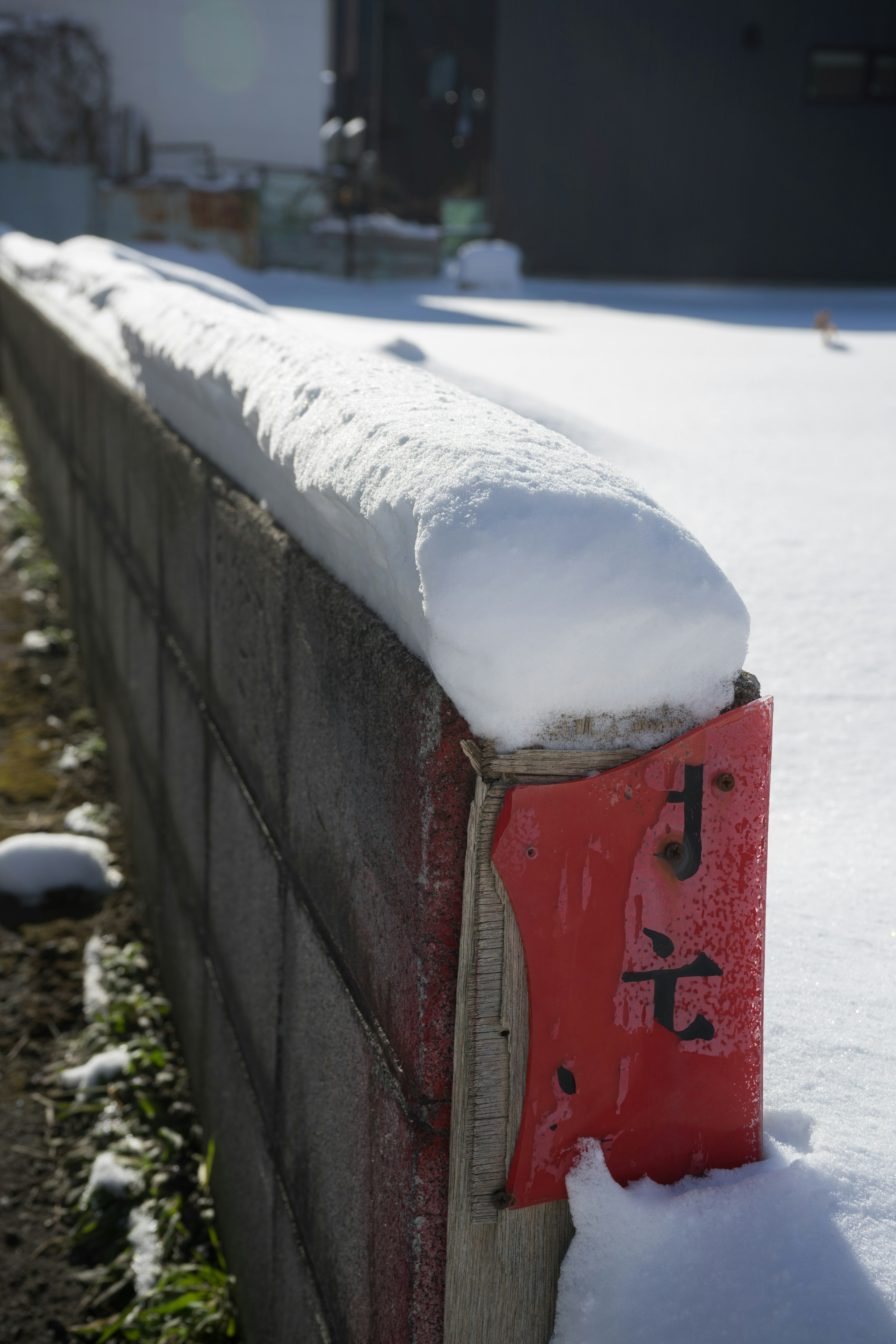 Schneebedeckter Blockwall mit charakteristischer Schneeform oben und rotem Abschnitt