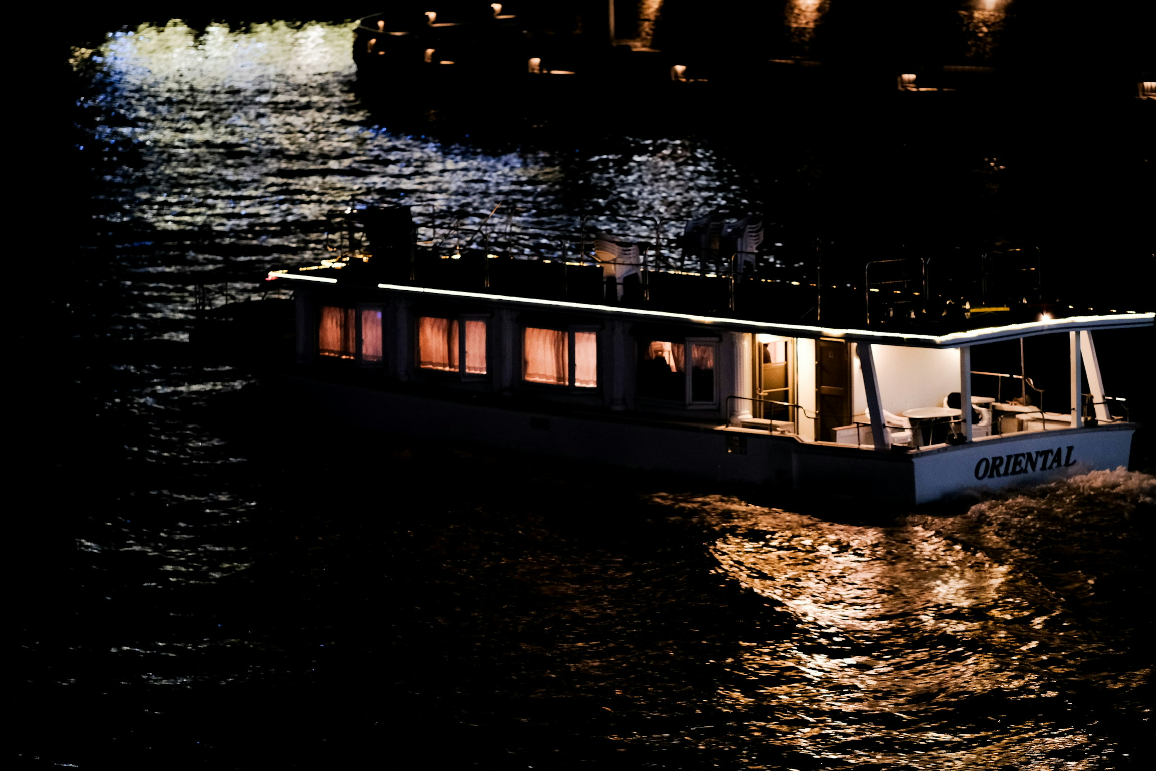 Un bateau illuminé flottant sur une rivière la nuit