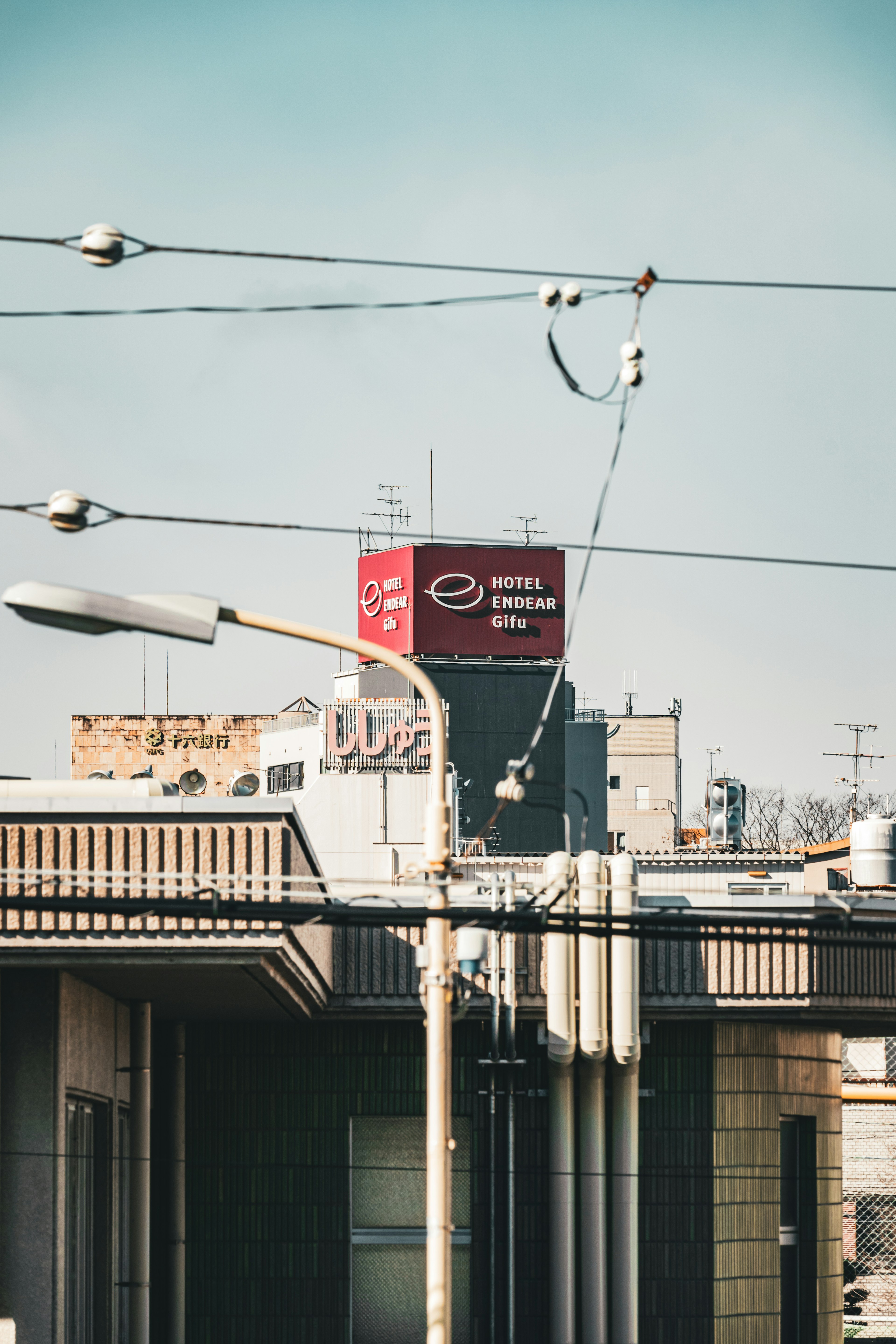 屋上にある赤い看板と電線が見える都市の景色