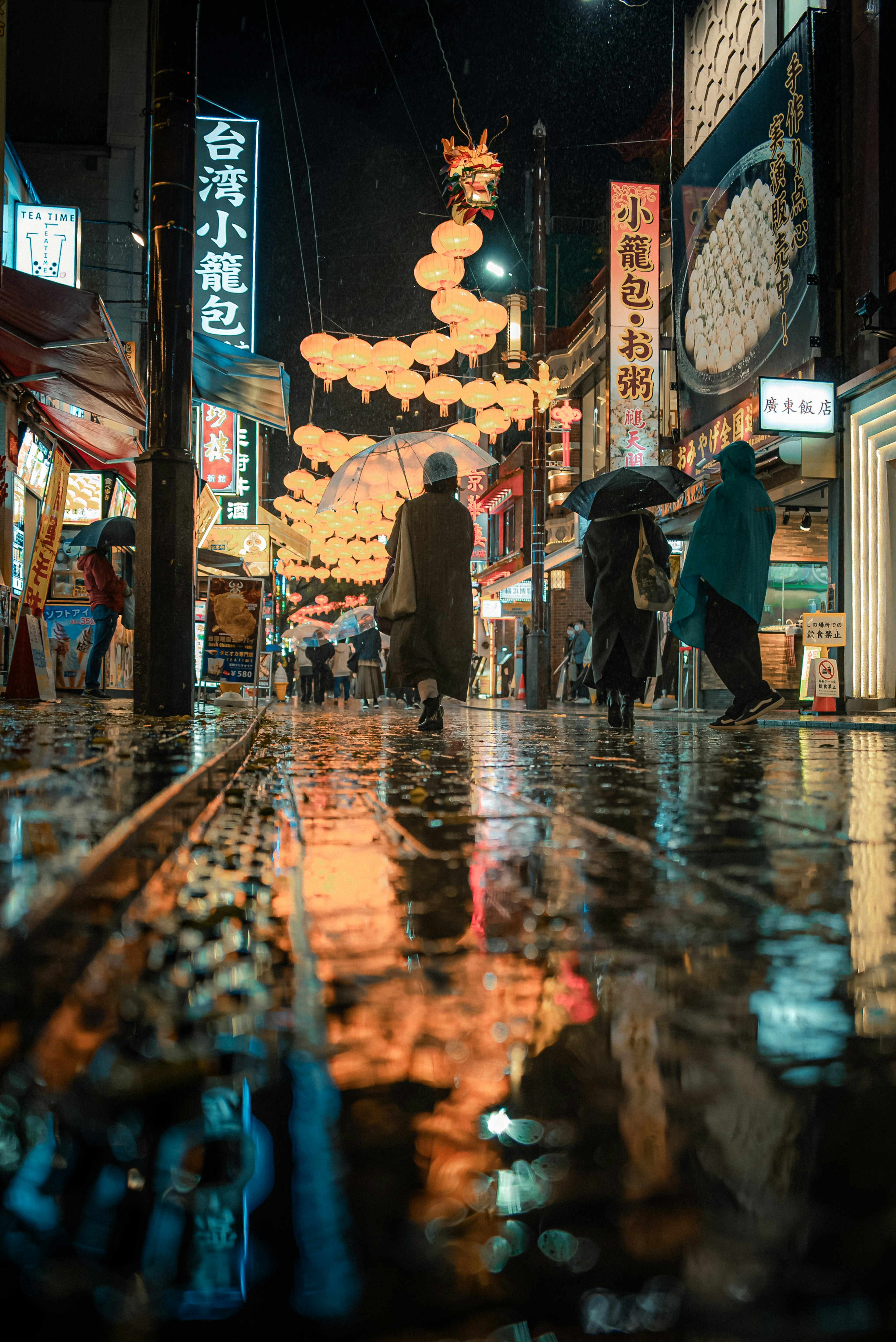 雨に濡れた街並みと提灯の光が反射する夜の風景