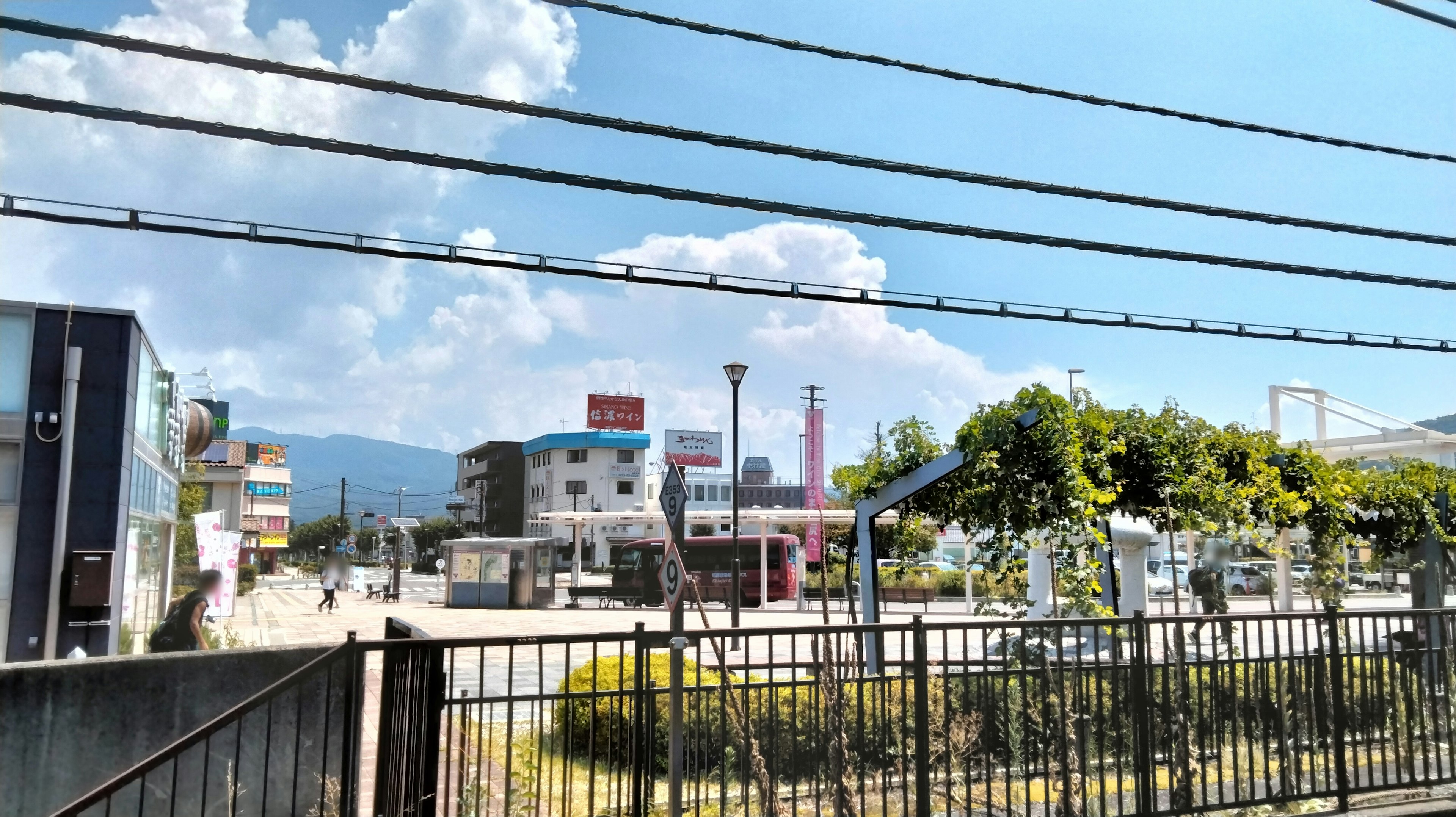 View of a train station area with blue sky and clouds featuring railway tracks and a fence