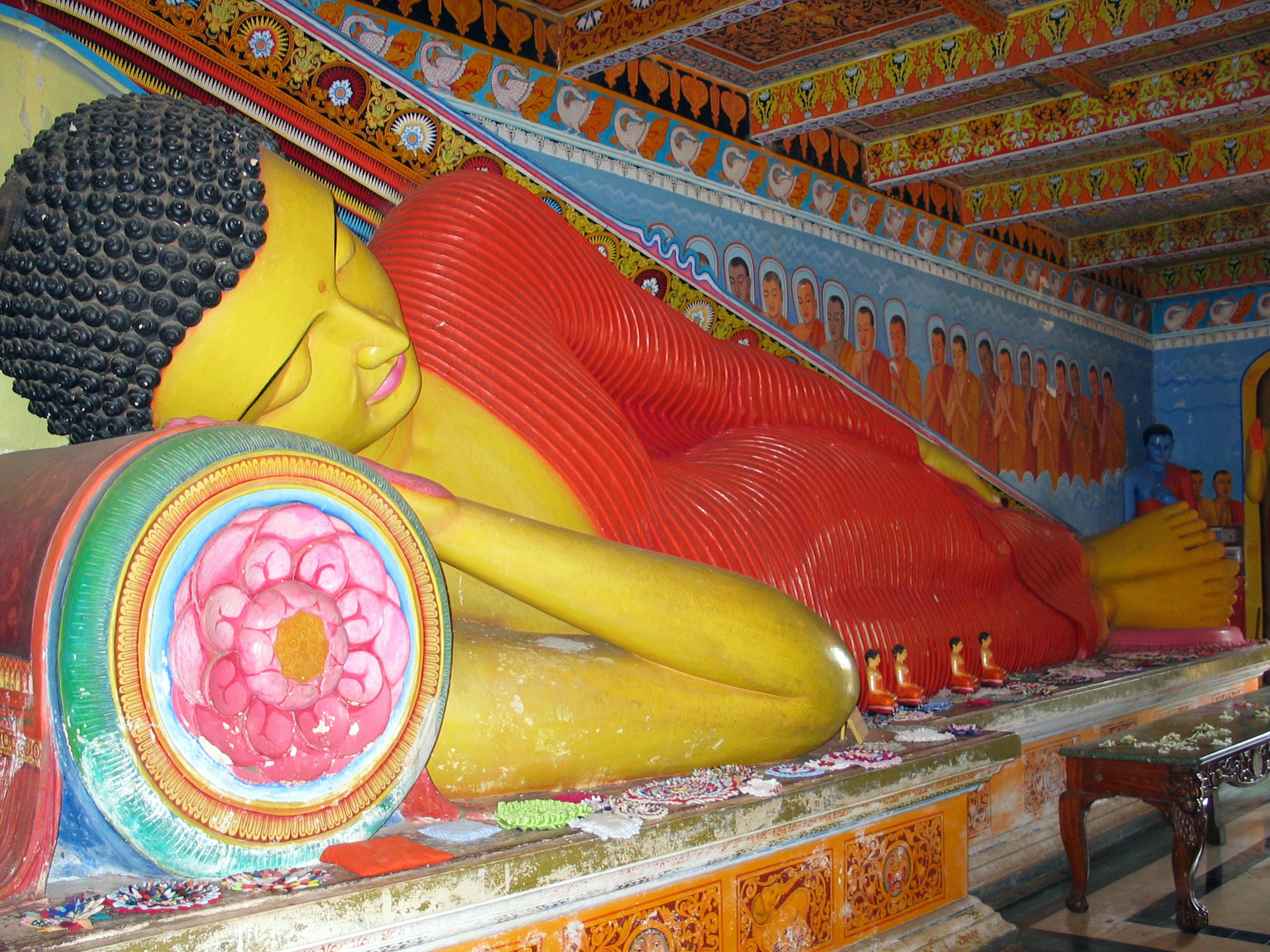 Reclining Buddha statue with vibrant wall paintings in temple interior