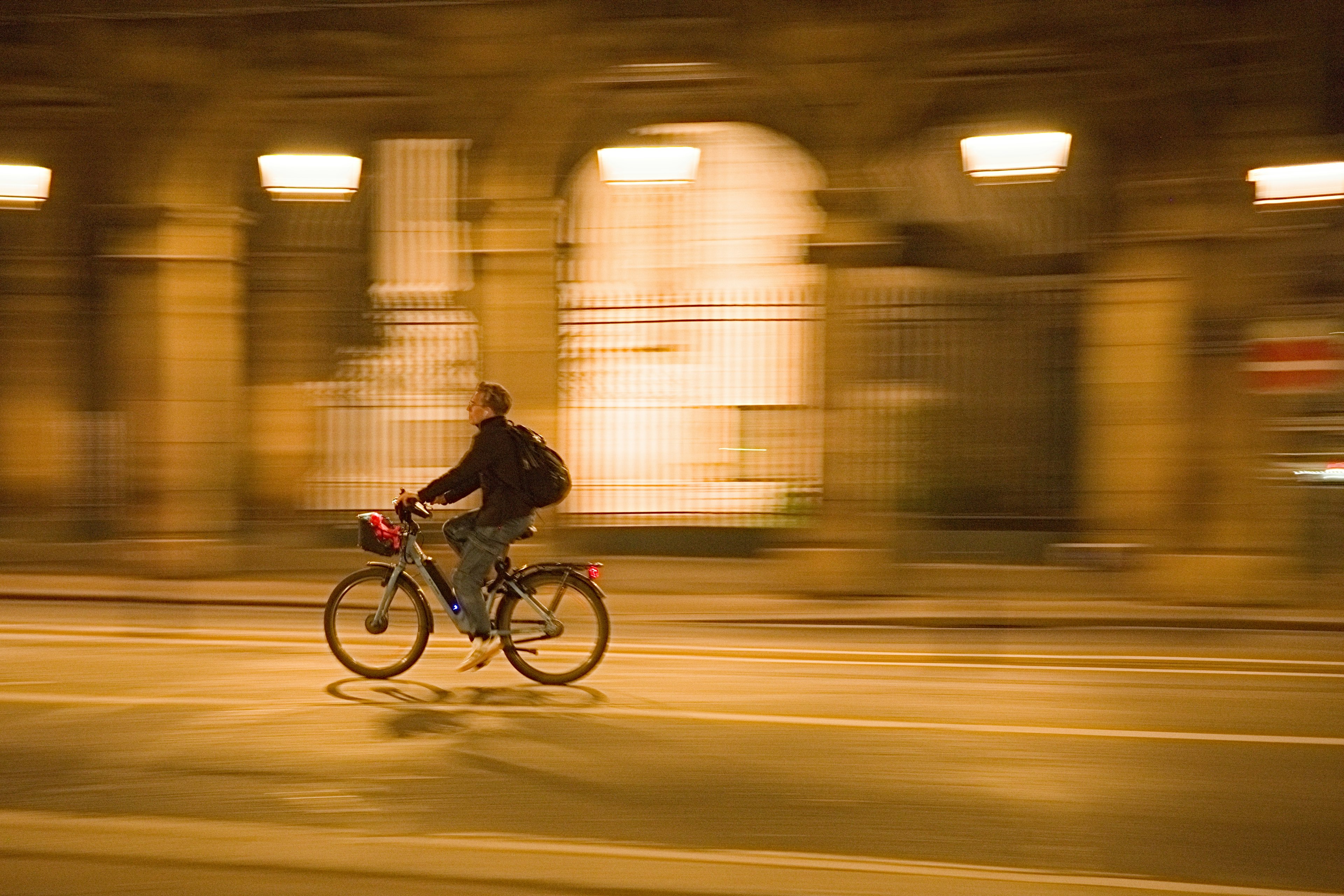 Imagen borrosa de un hombre montando en bicicleta por la ciudad de noche