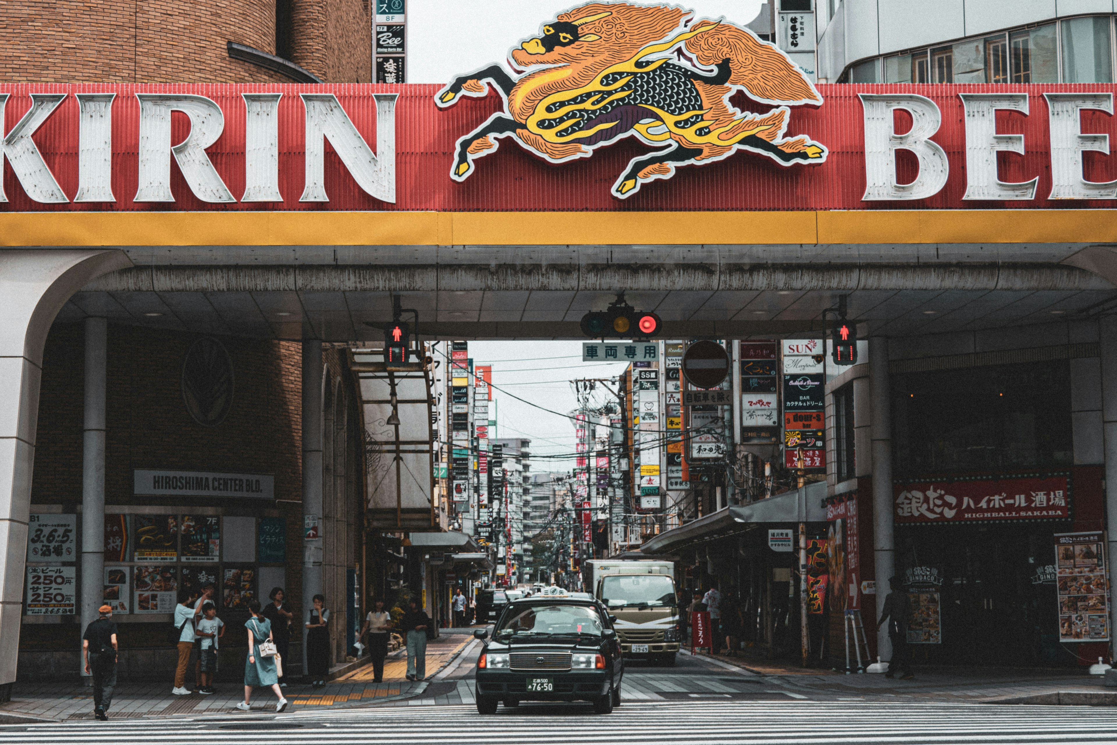 Street scene with a car and pedestrians under a Kirin Beer sign