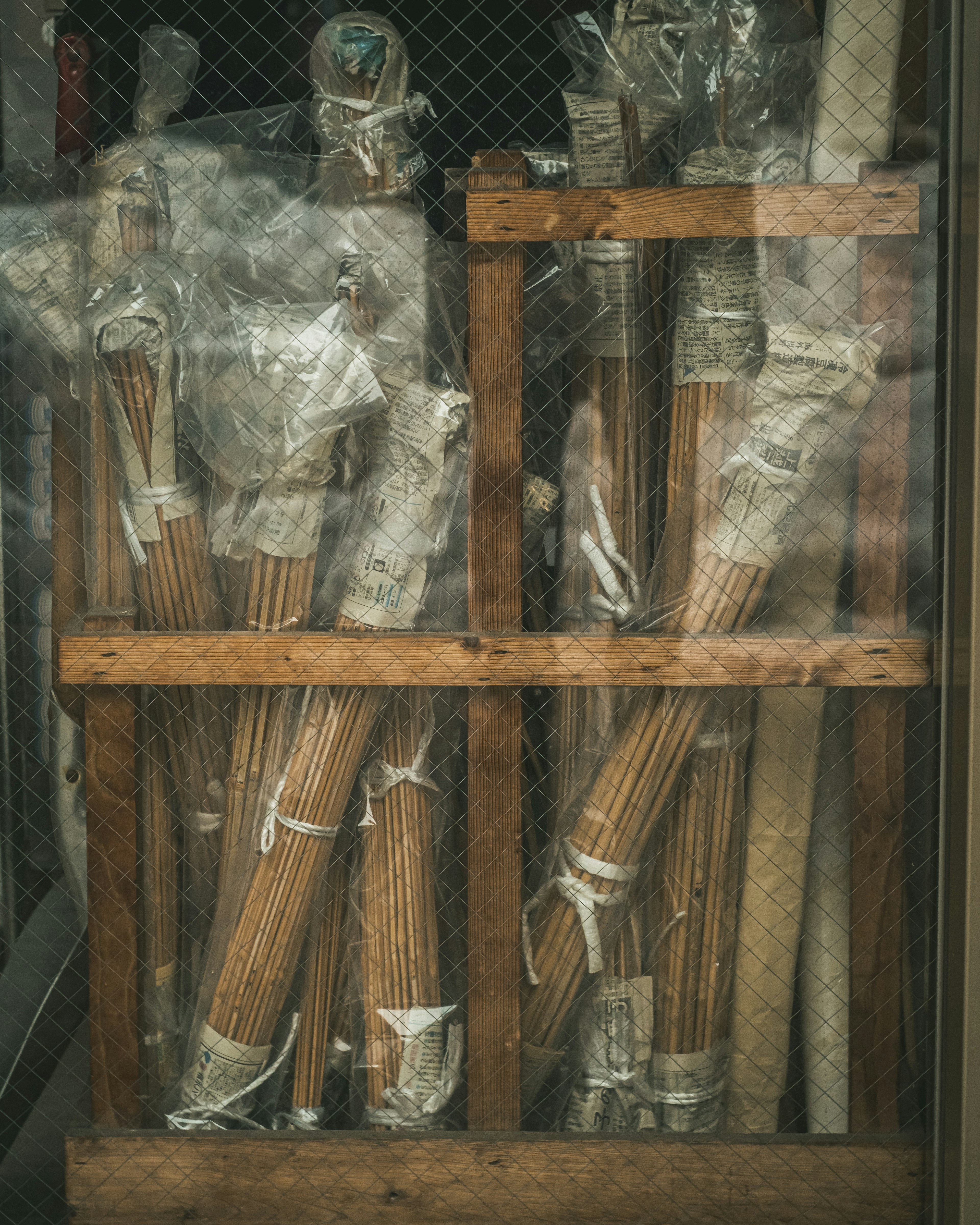 Bundles of long rods wrapped in plastic stored in a wooden frame