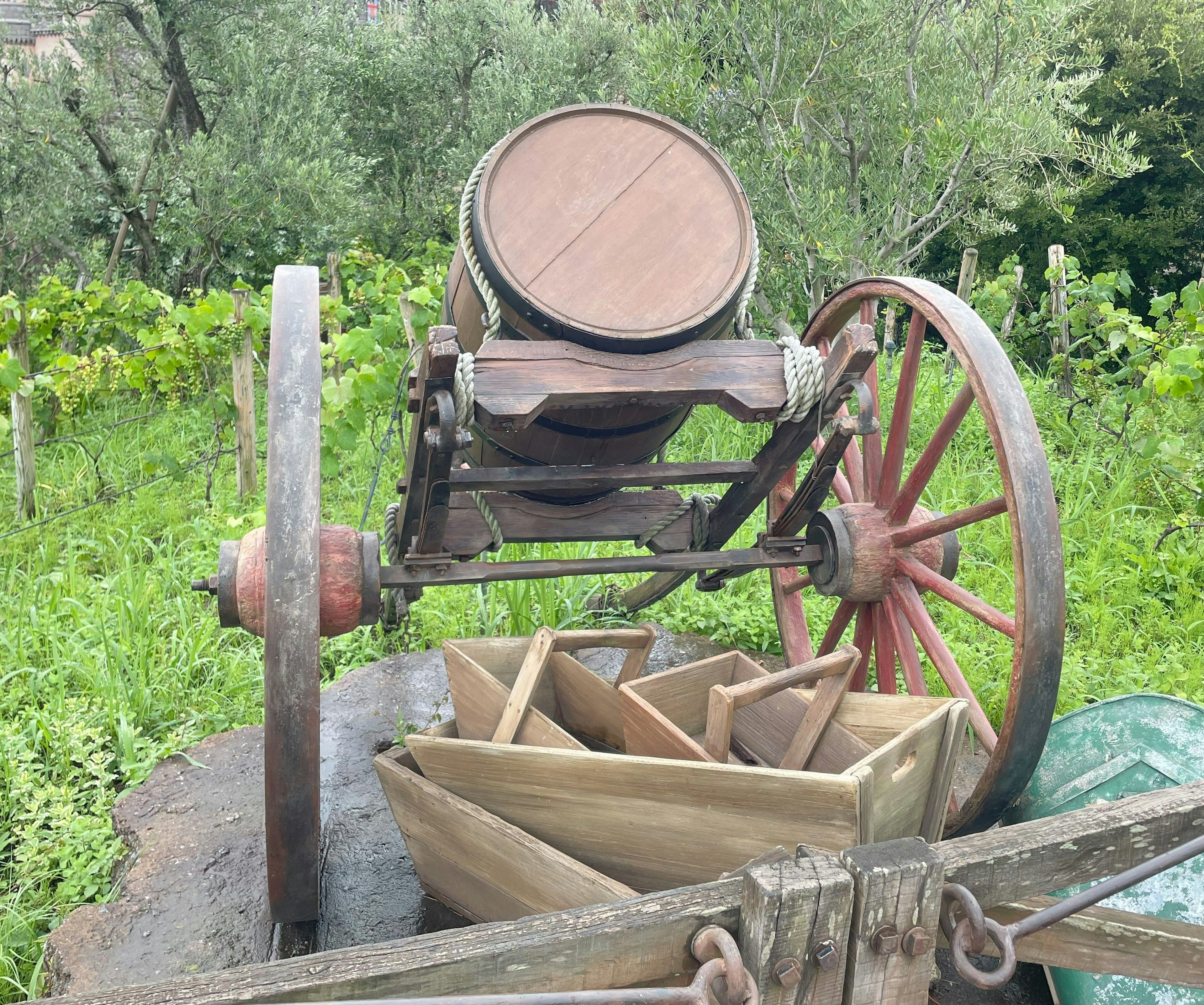 Ein antiker Holzwagen mit einem Fass und Holztrögen vor grünem Hintergrund