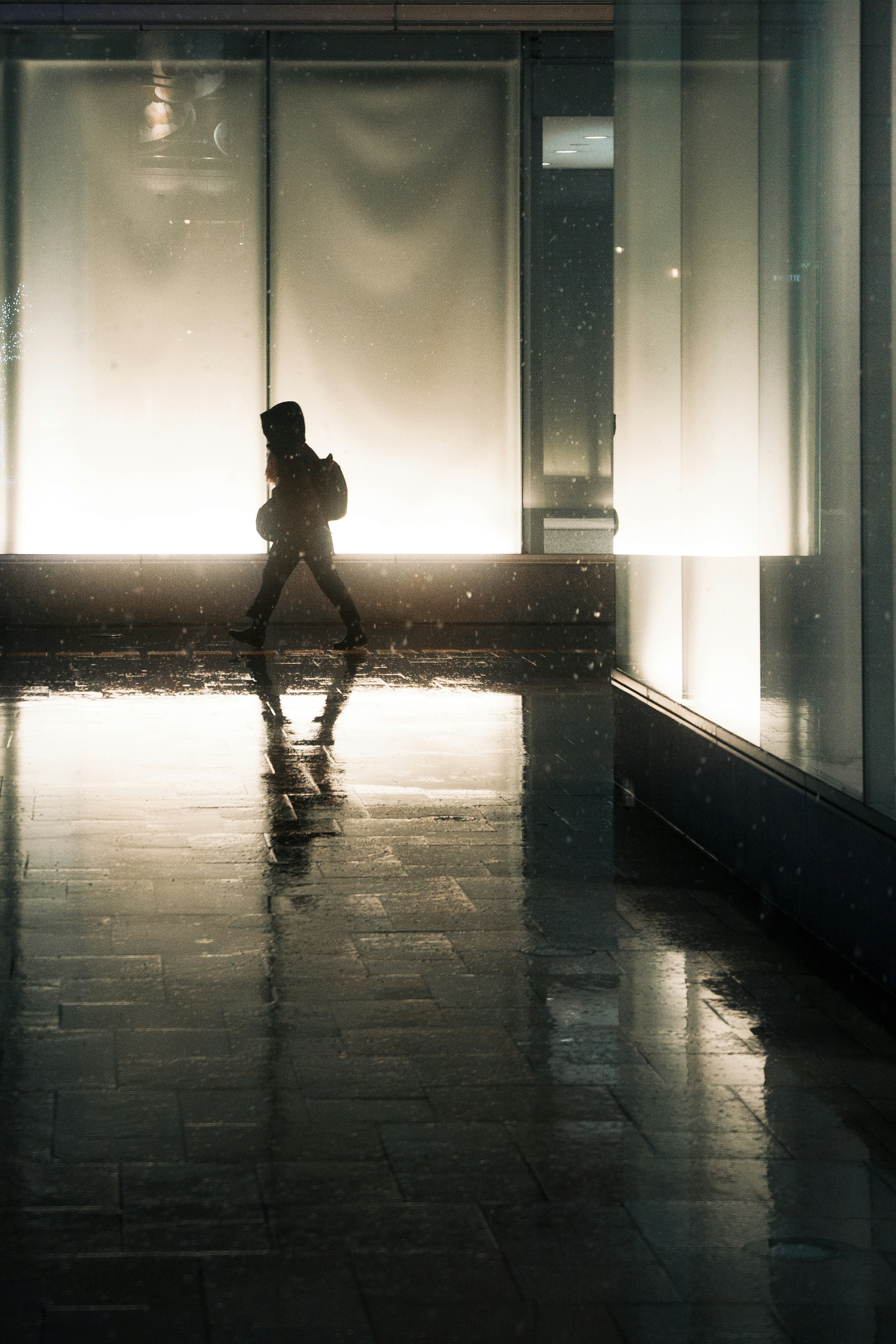 Silhouette di una persona che cammina in uno spazio debolmente illuminato