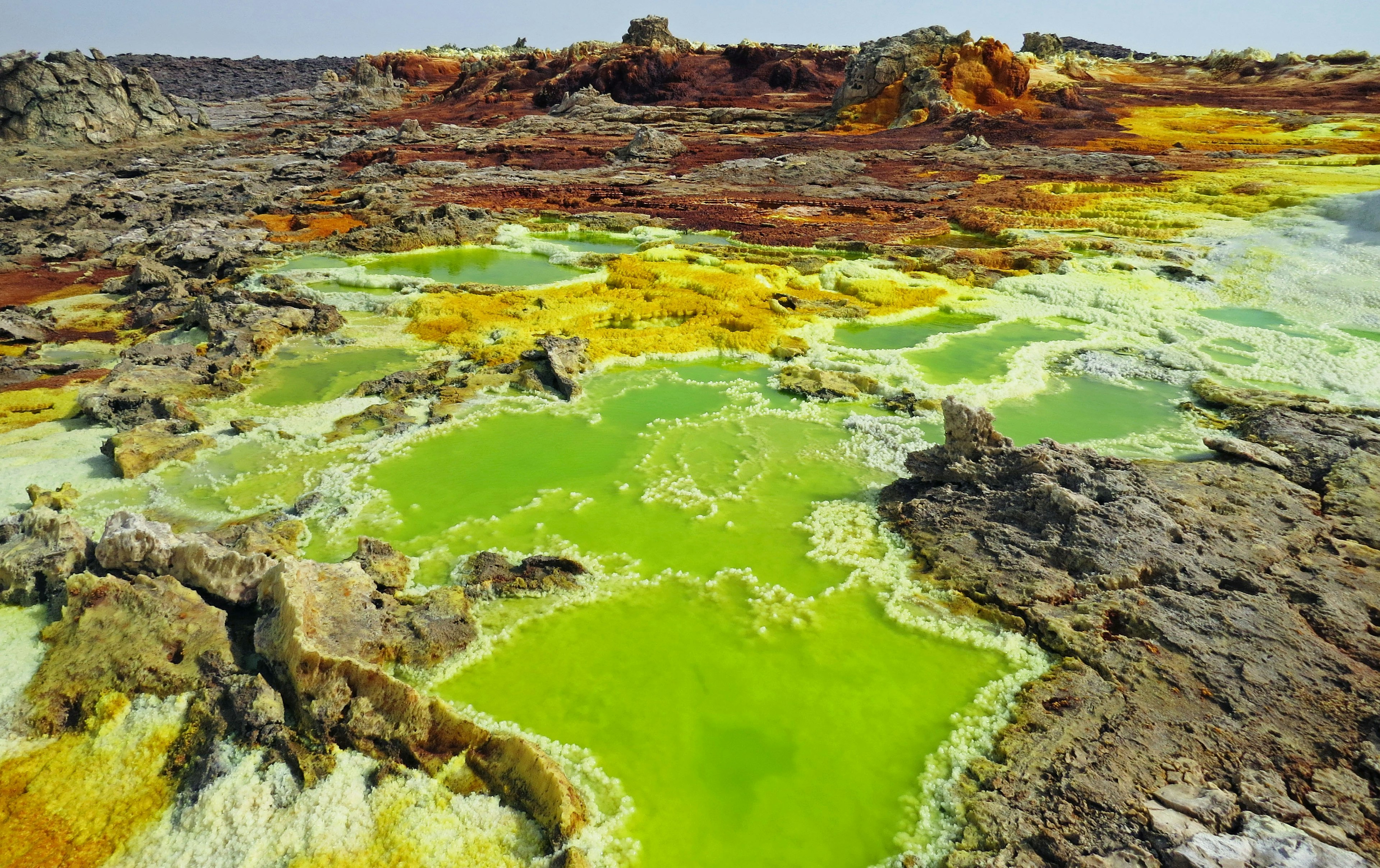 Lanskap geotermal berwarna-warni di Danakil dengan kolam hijau dan formasi berbatu