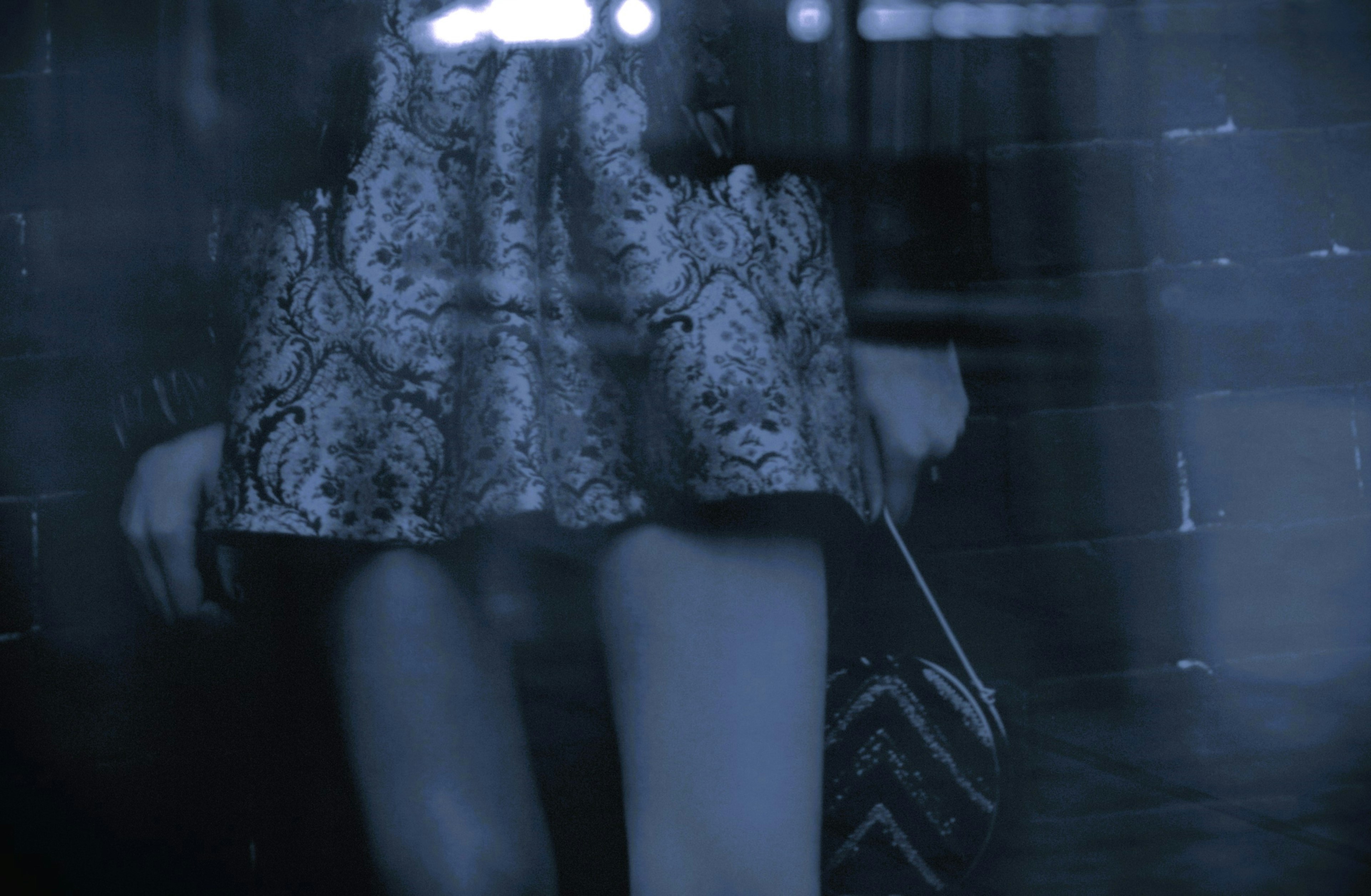 Image of a woman's legs holding a skirt against a blue-toned background