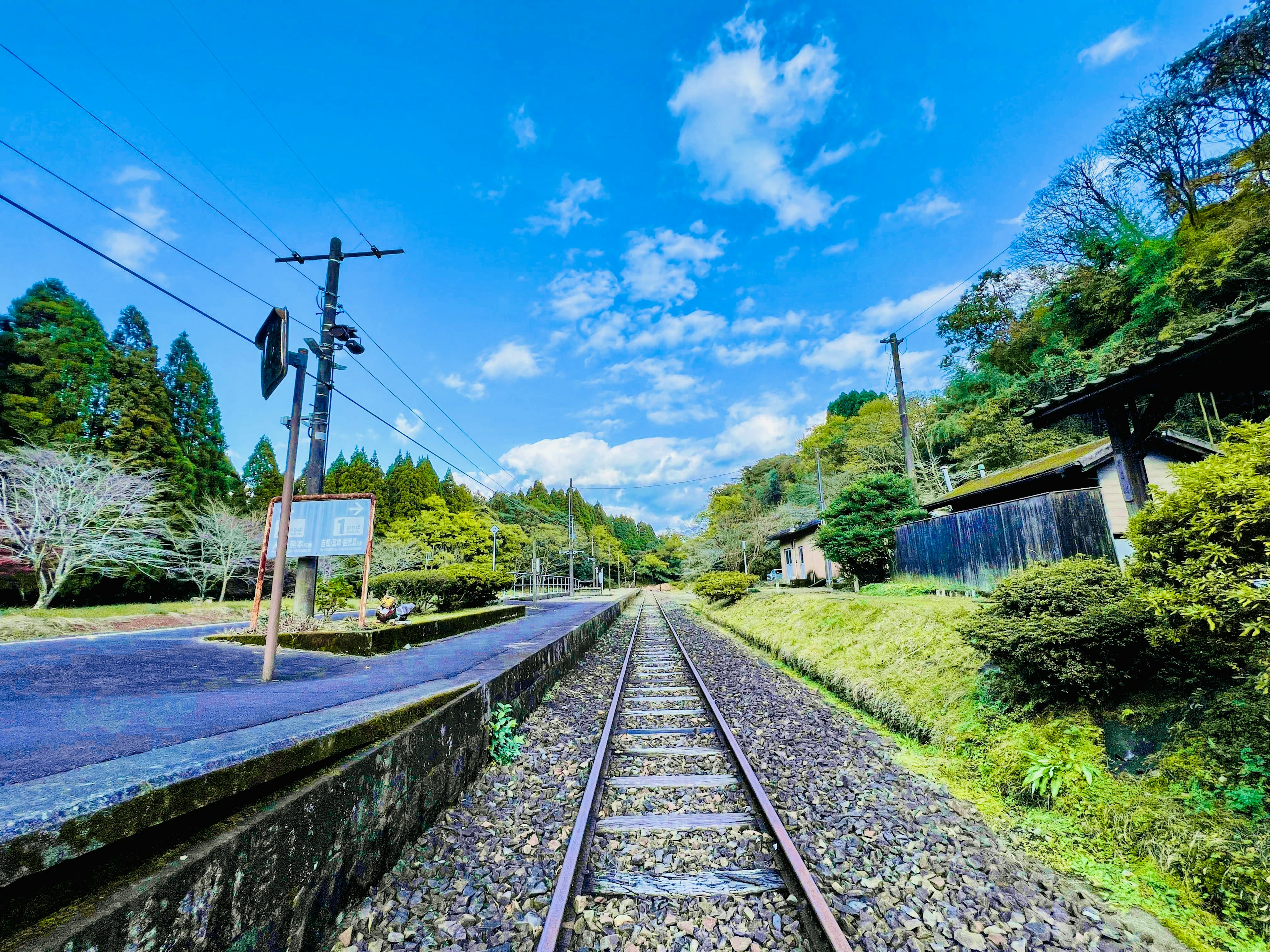 静かな田舎の鉄道駅の風景 緑豊かな丘と青い空