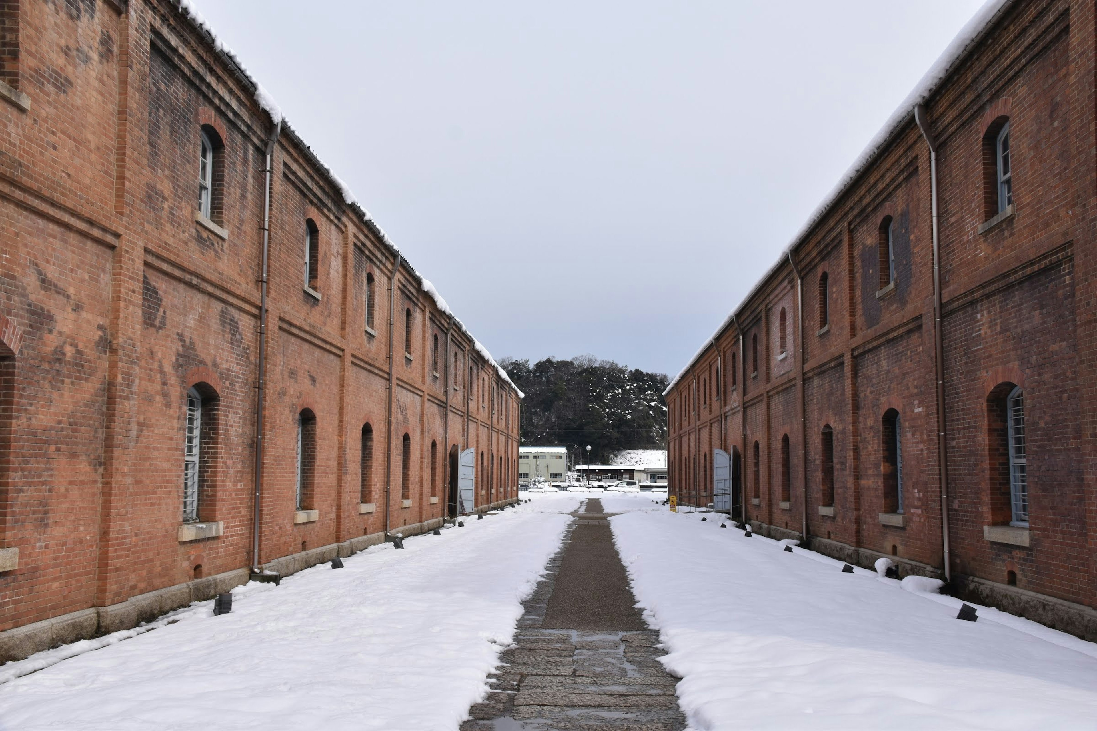 Camino cubierto de nieve entre edificios de ladrillo rojo