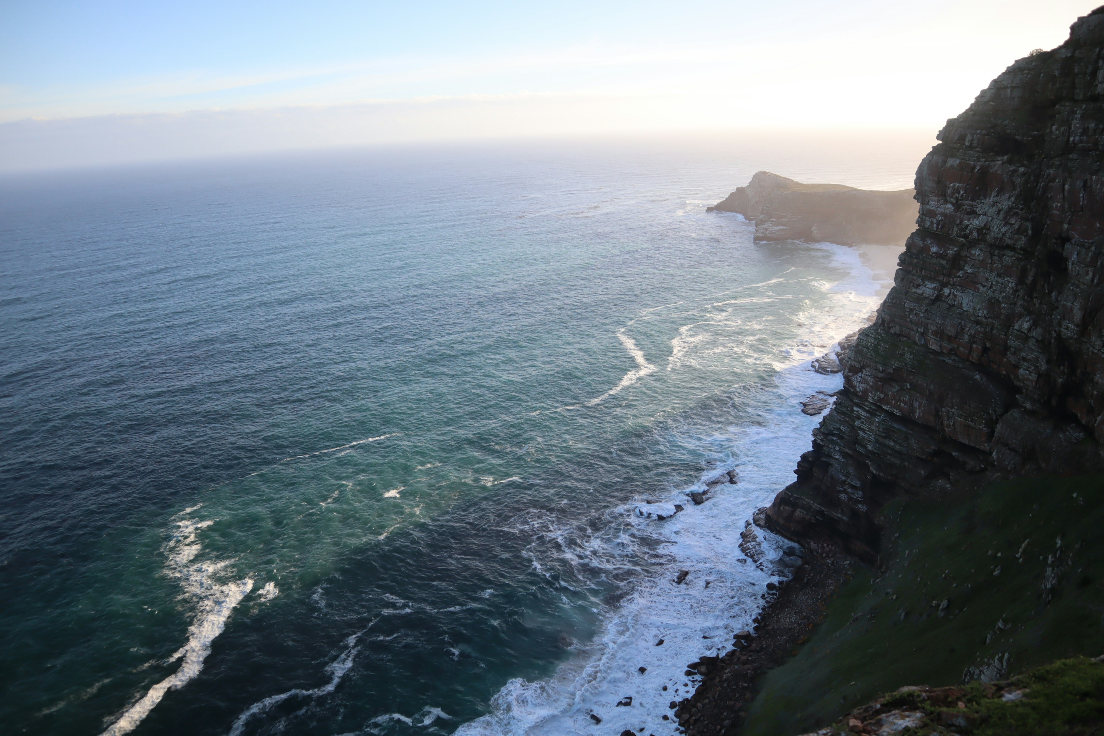 Costa panoramica con onde che si infrangono e scogliere rocciose