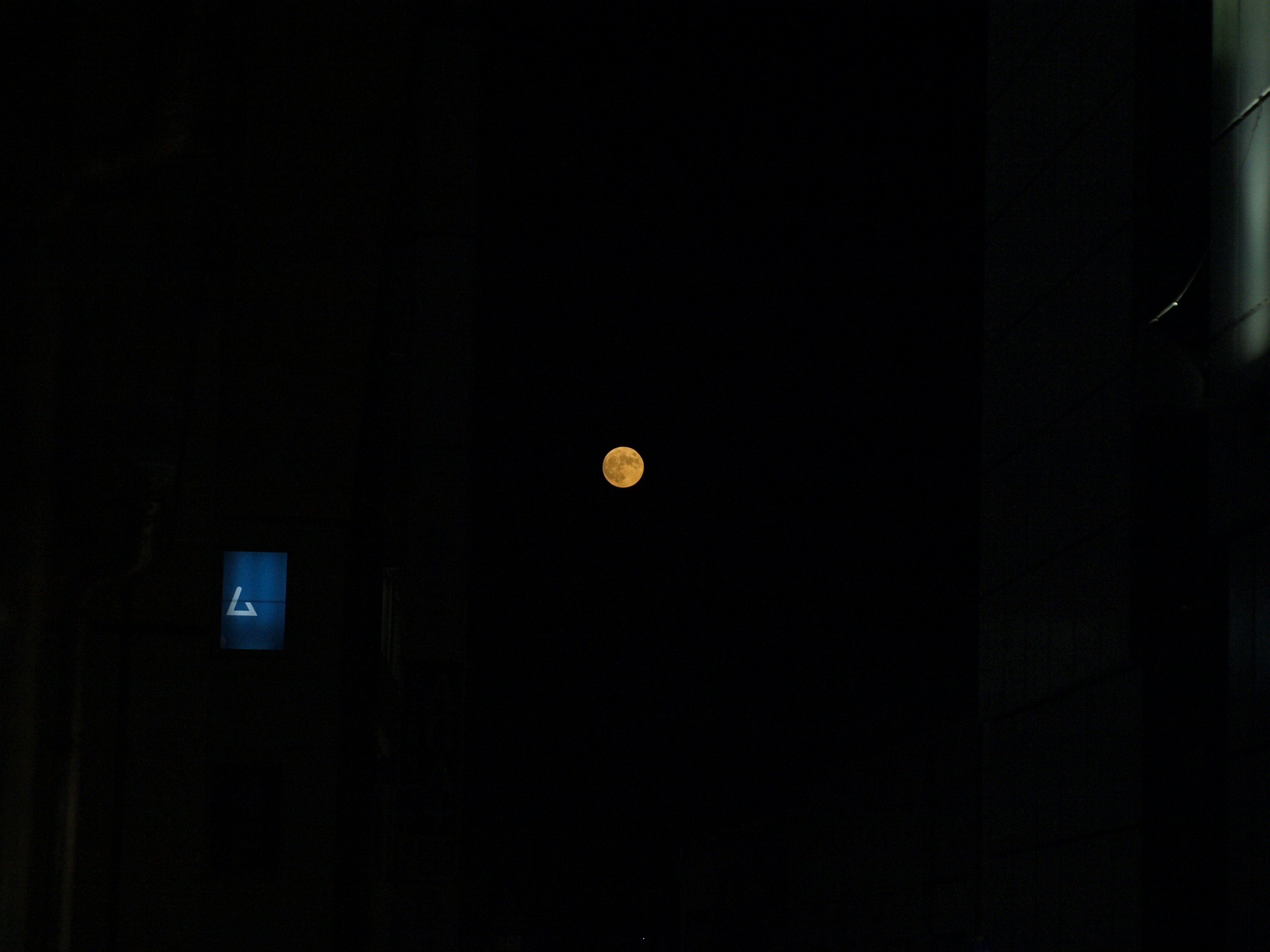 Luna naranja flotando en el cielo nocturno con un fondo oscuro