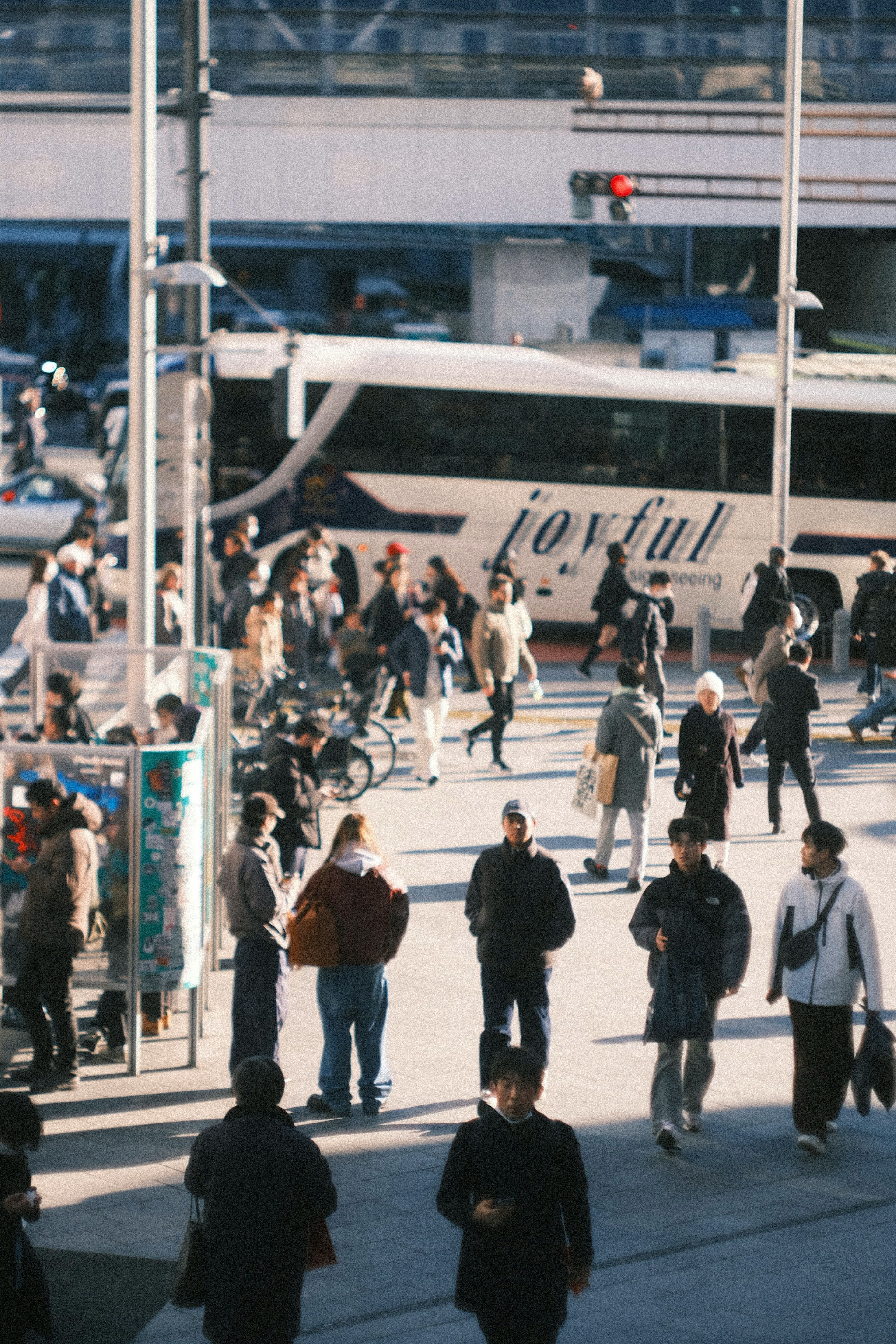 A bustling urban scene with numerous people at a bus stop