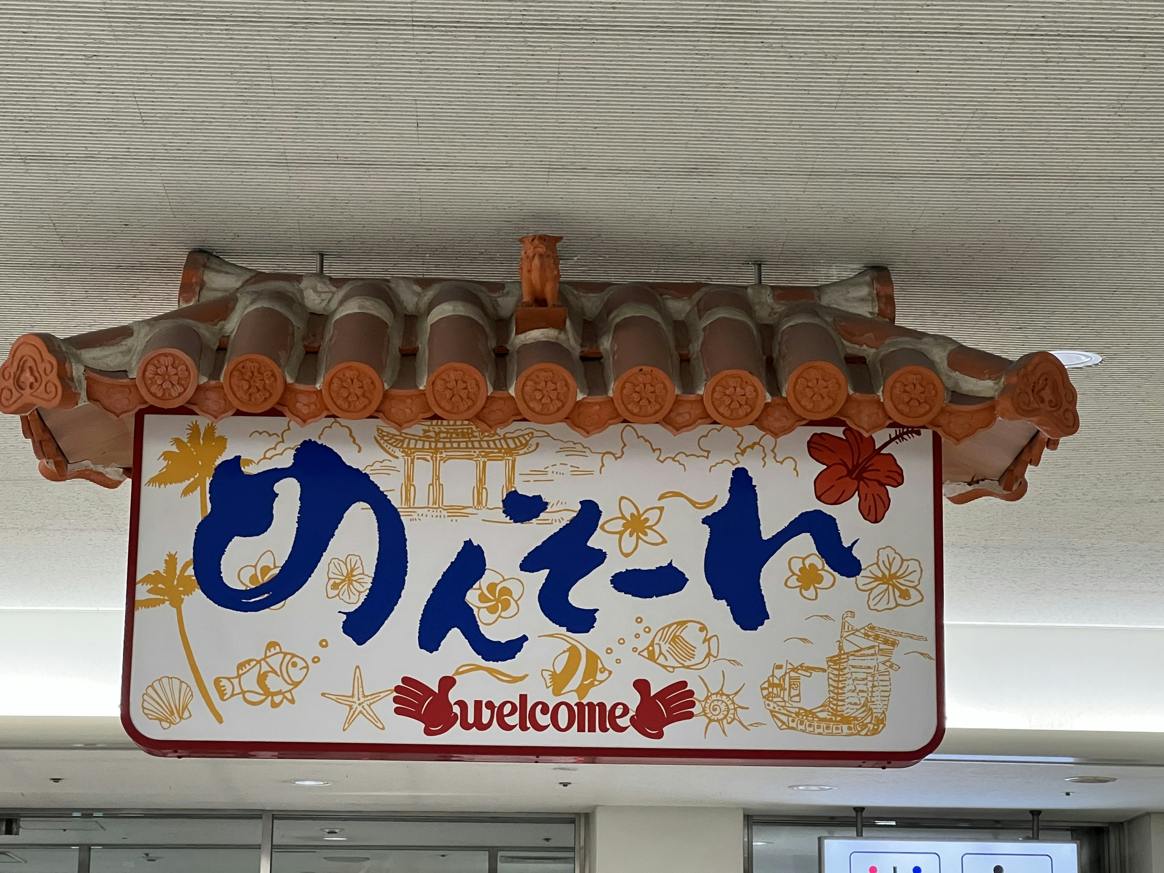 Welcome sign with Japanese characters and Okinawan-style roof