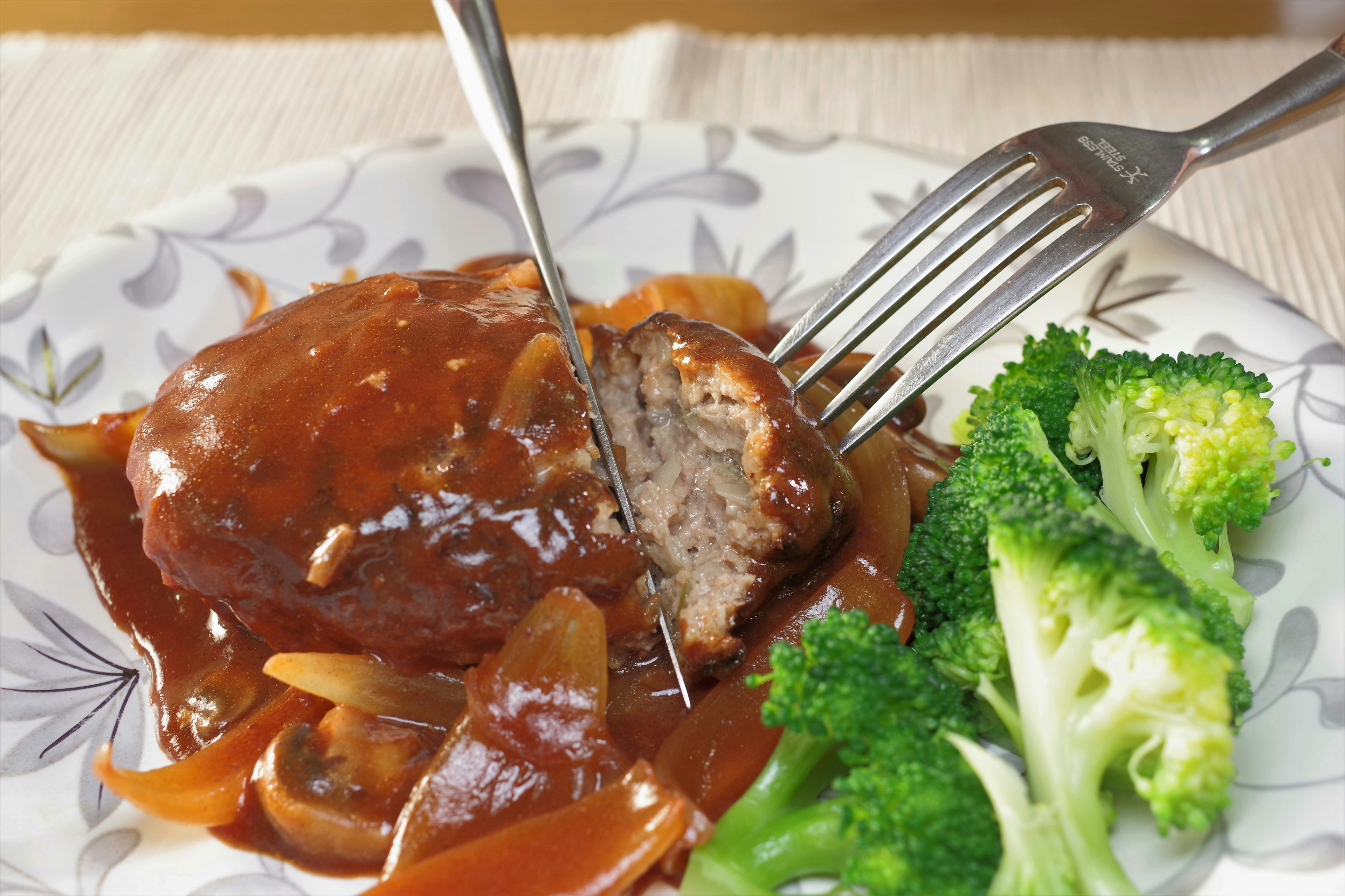 Teller mit Hamburgersteak in Soße und Brokkoli