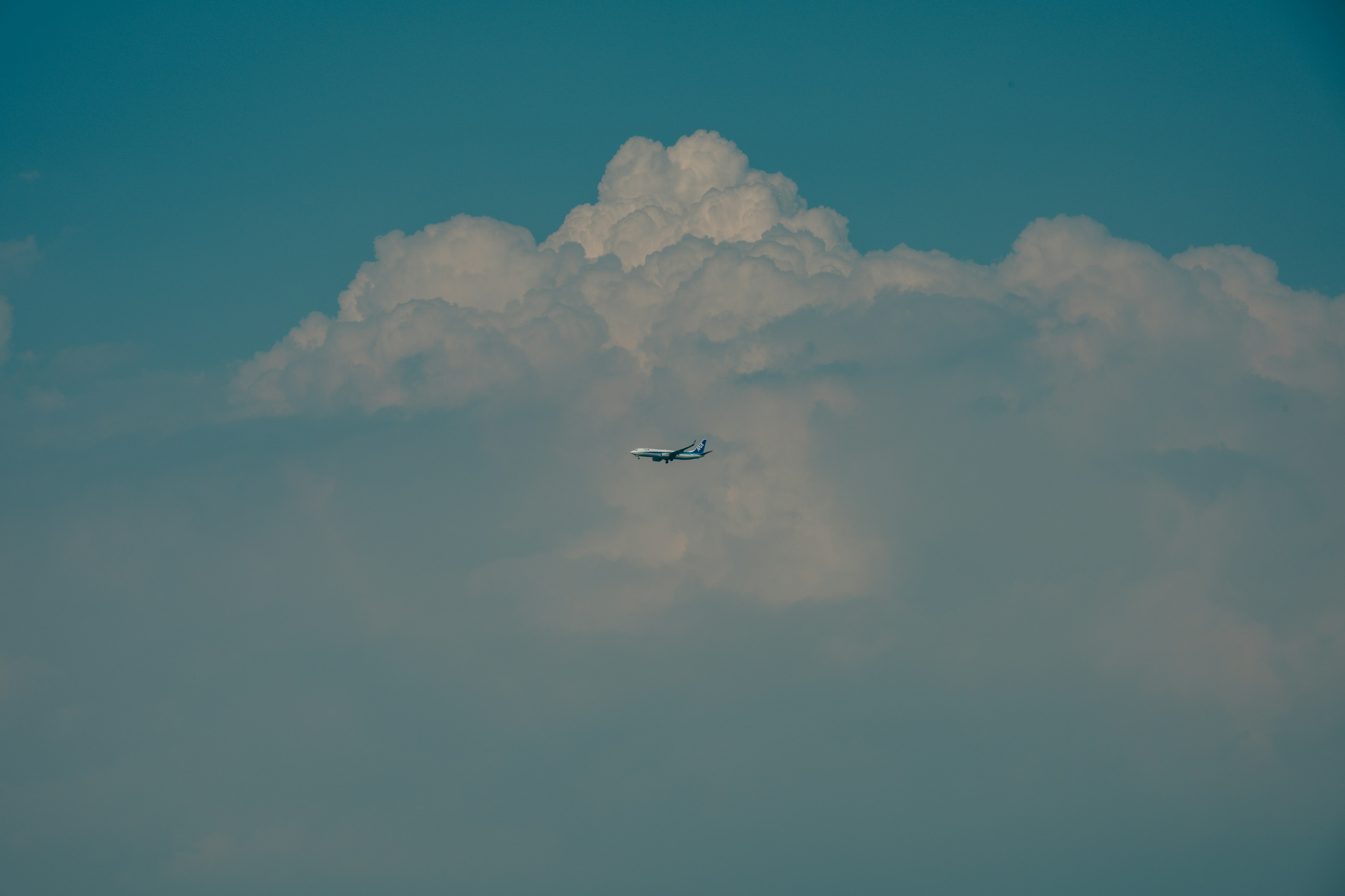 Pesawat terbang di atas awan di langit biru