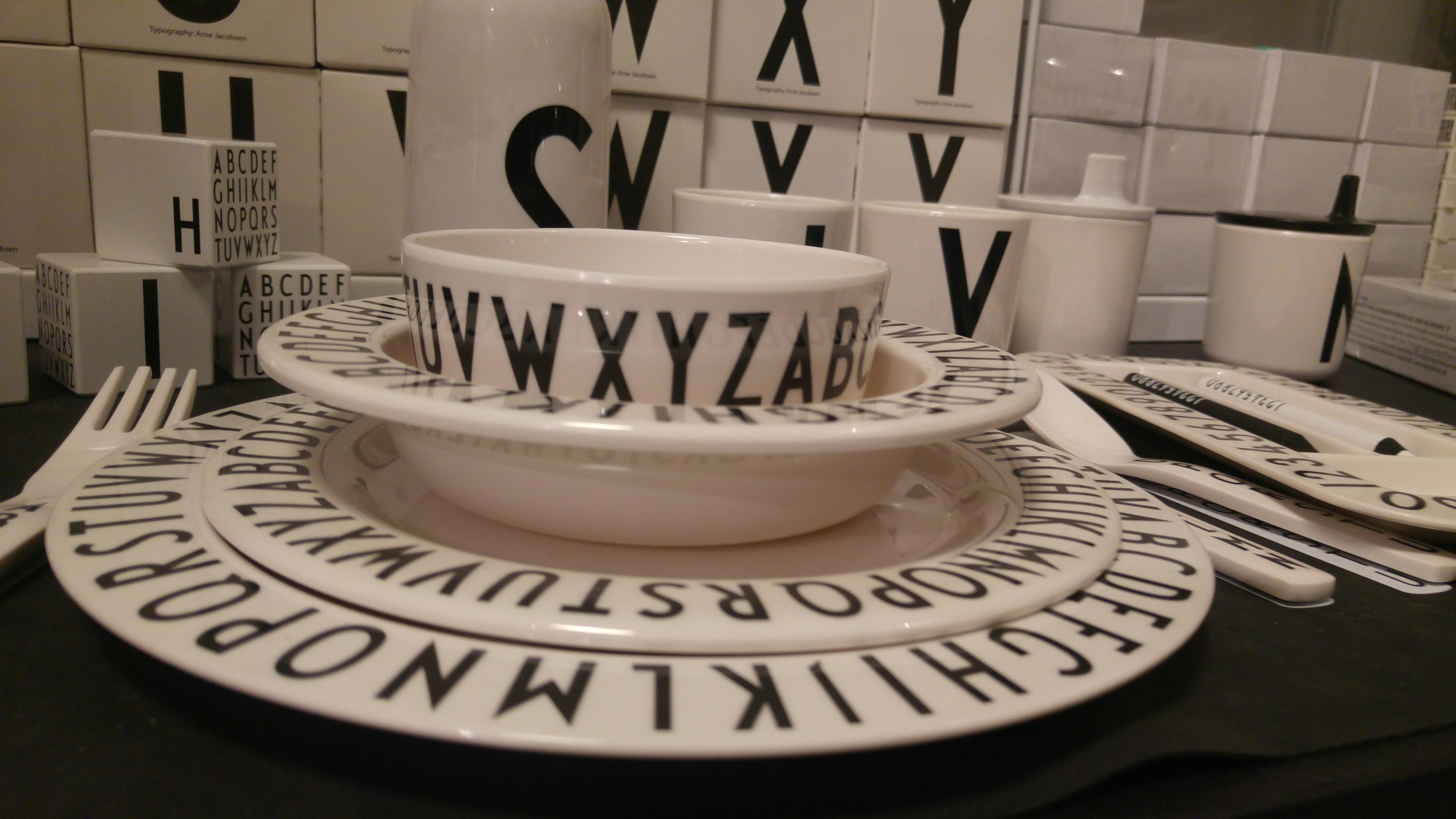 Table setting featuring white dishes with black alphabet letters