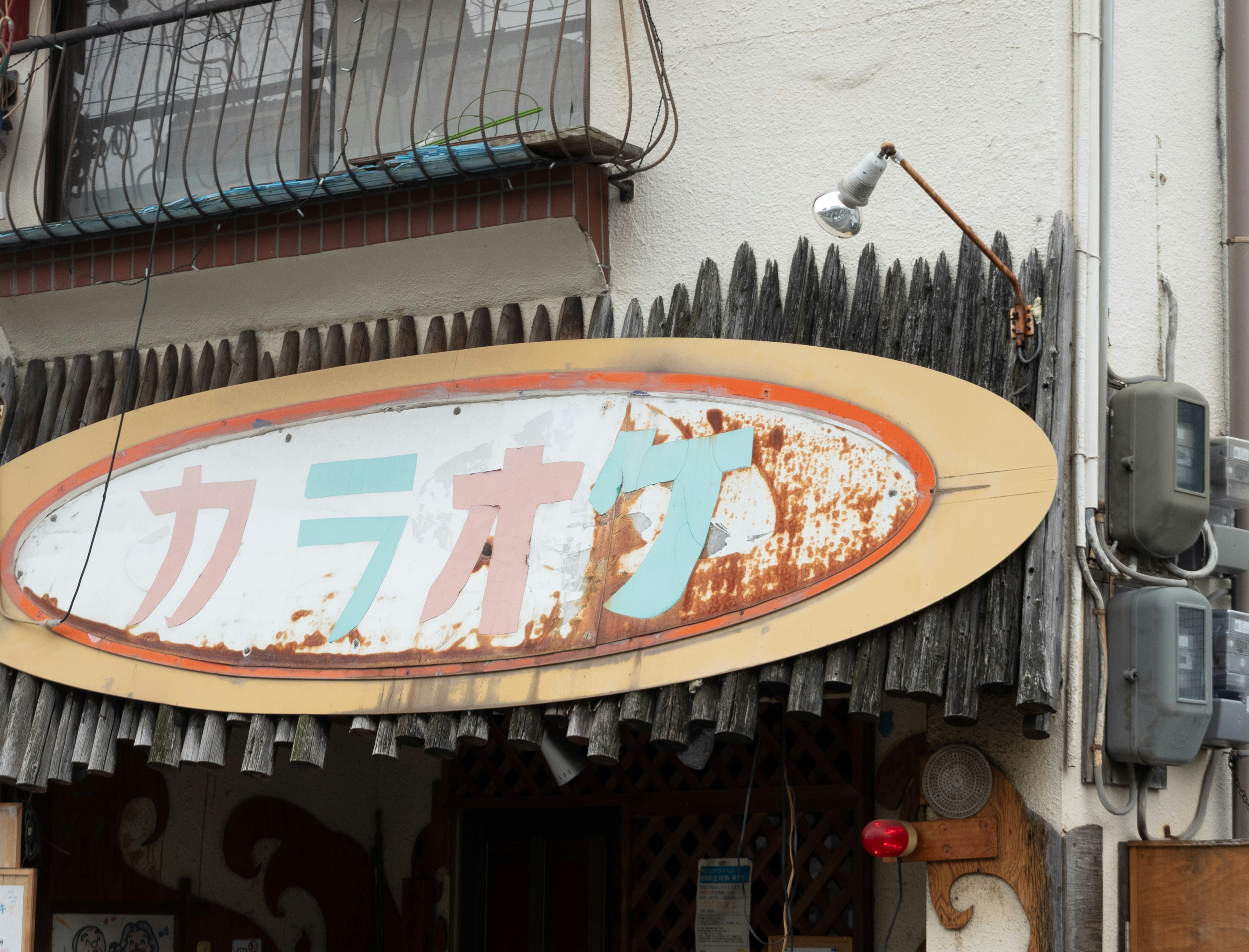 Karaoke sign attached to a weathered storefront