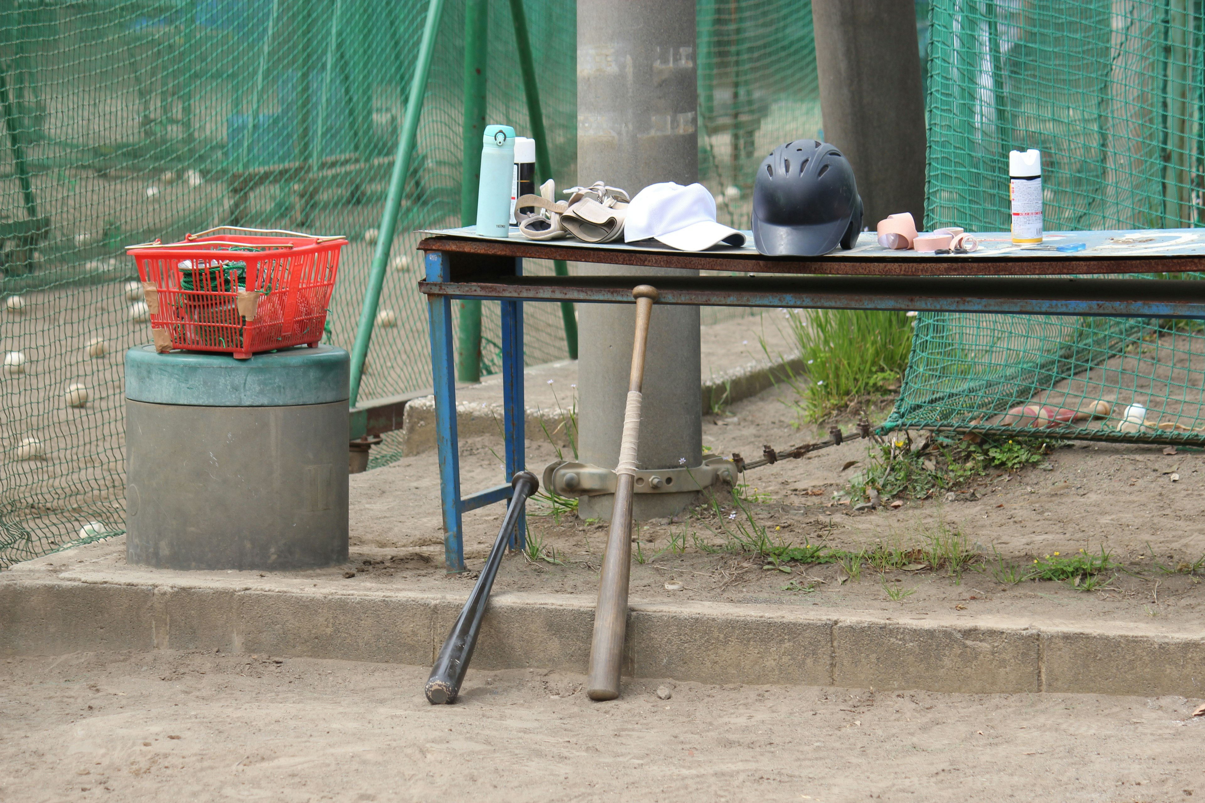 야구 연습장 테이블에 배트, 헬멧, 공 및 다양한 장비가 놓여 있음